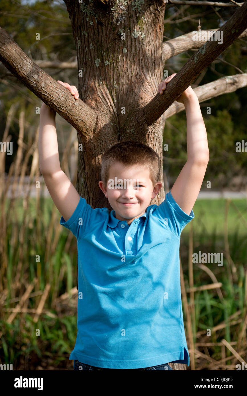 Young boy leaning on Oak tree at park, portrait Banque D'Images