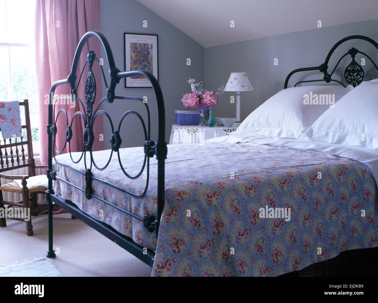 Couverture A Motifs De Roses Et Blancs Ornes De Coussins Lit En Fer Forge Noir Gris Pale Dans Une Chambre Mansardee Avec Rideaux Rose Photo Stock Alamy