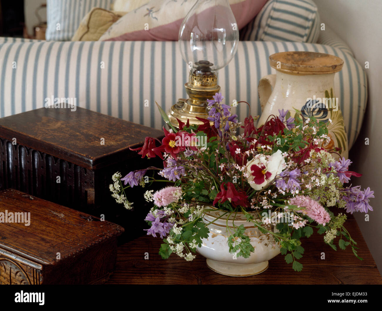 Fleurs d'été dans la soupière sur la table de nuit avec des caisses en bois dans salon cottage Banque D'Images Fleurs d'été dans la soupière sur la table de nuit avec des caisses en bois dans salon cottage Banque D'Images