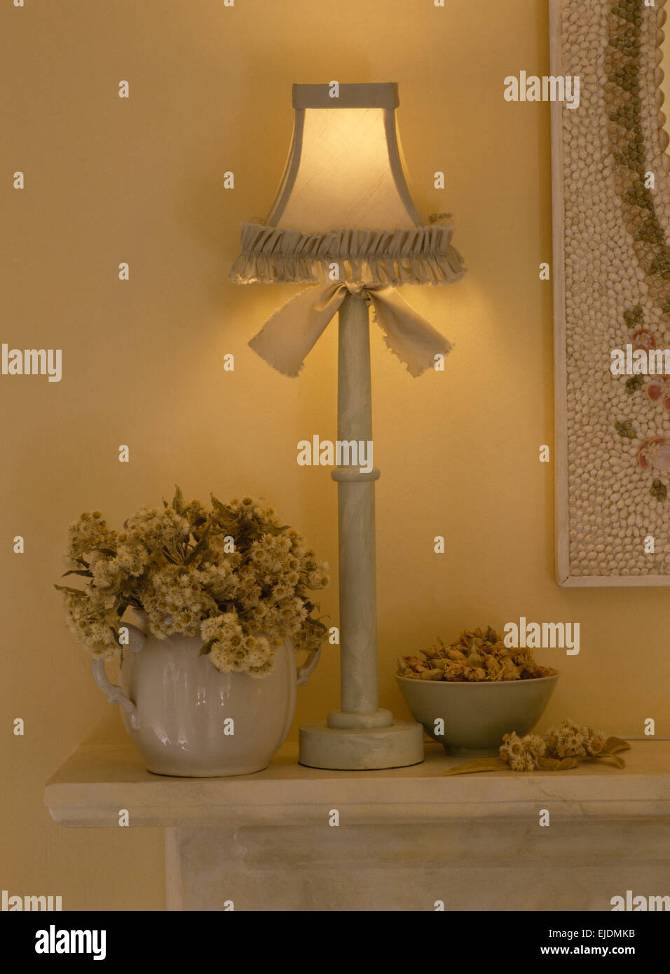 Lampe peinte attaché avec un noeud sur la cheminée avec vase de fleurs séchées Banque D'Images
