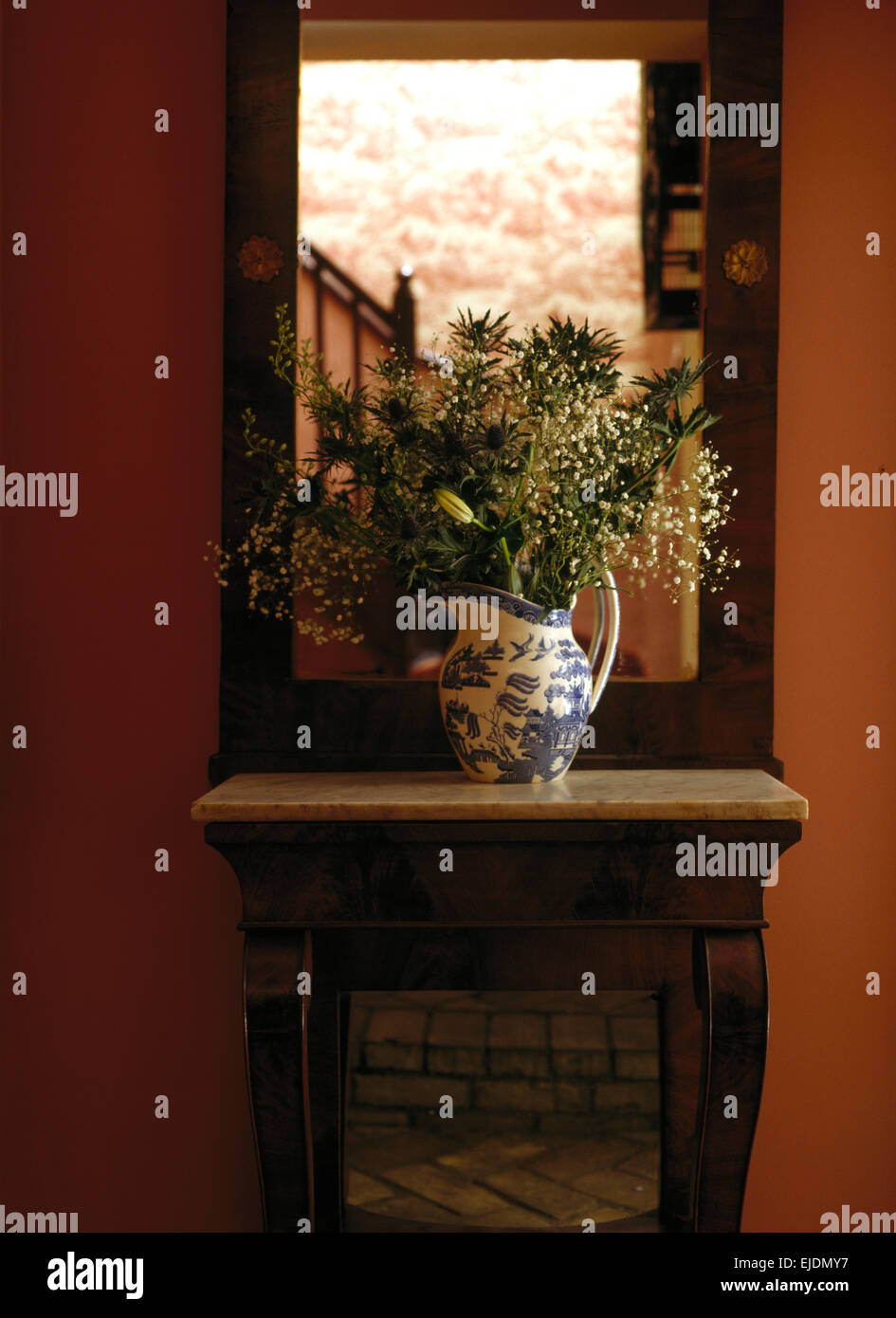 Miroir sur le mur au-dessus de table avec vase de fleurs d'été en pays hall Banque D'Images