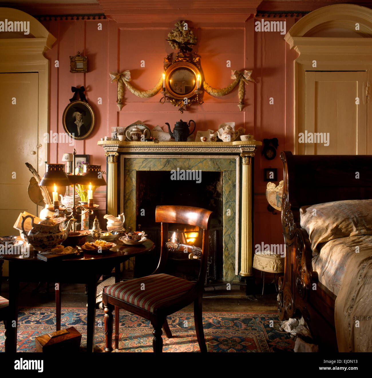 Meubles anciens dans un style géorgien rose chambre avec un miroir doré orné au-dessus de la cheminée Banque D'Images