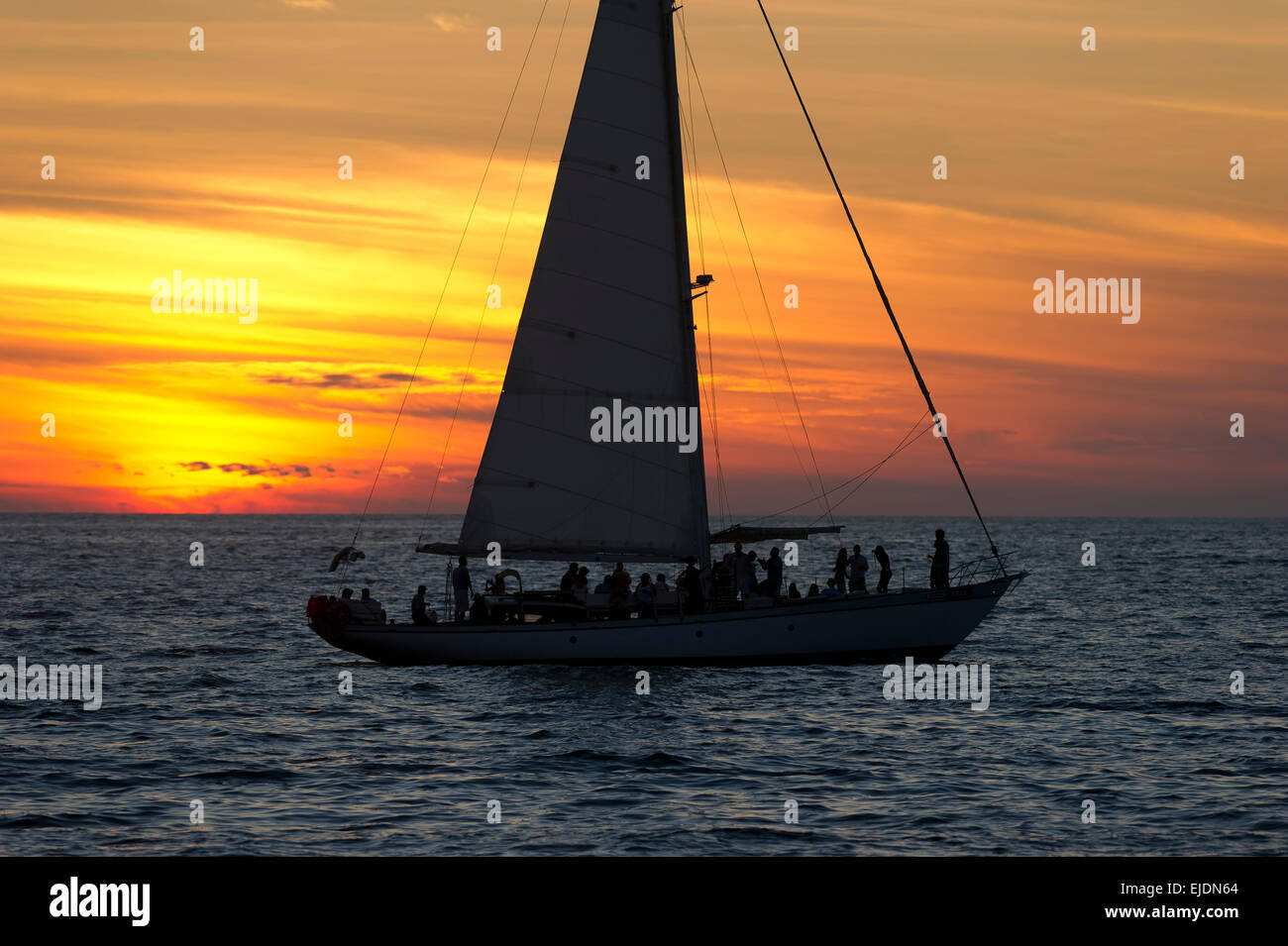 Un voilier navigue plein de gens au coucher du soleil. Banque D'Images