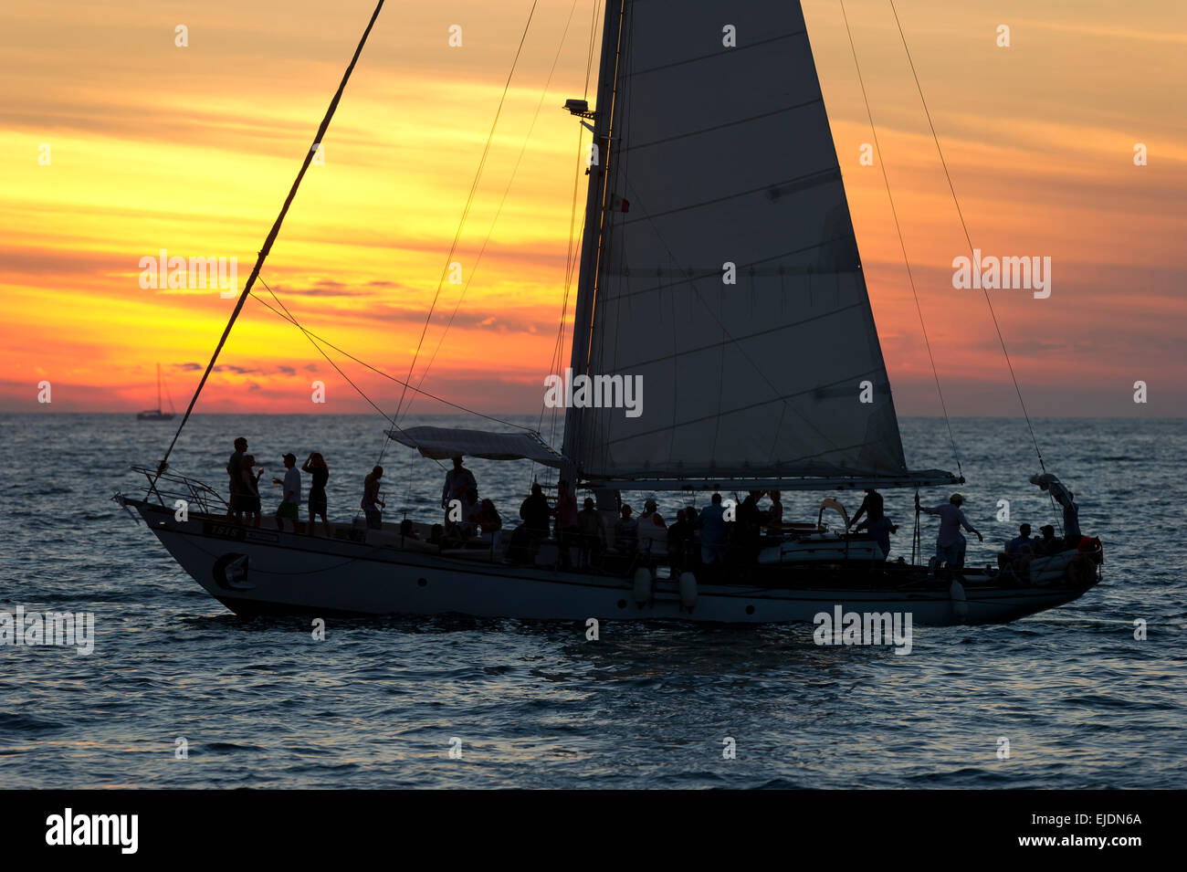 Un voilier navigue plein de gens au coucher du soleil. Banque D'Images