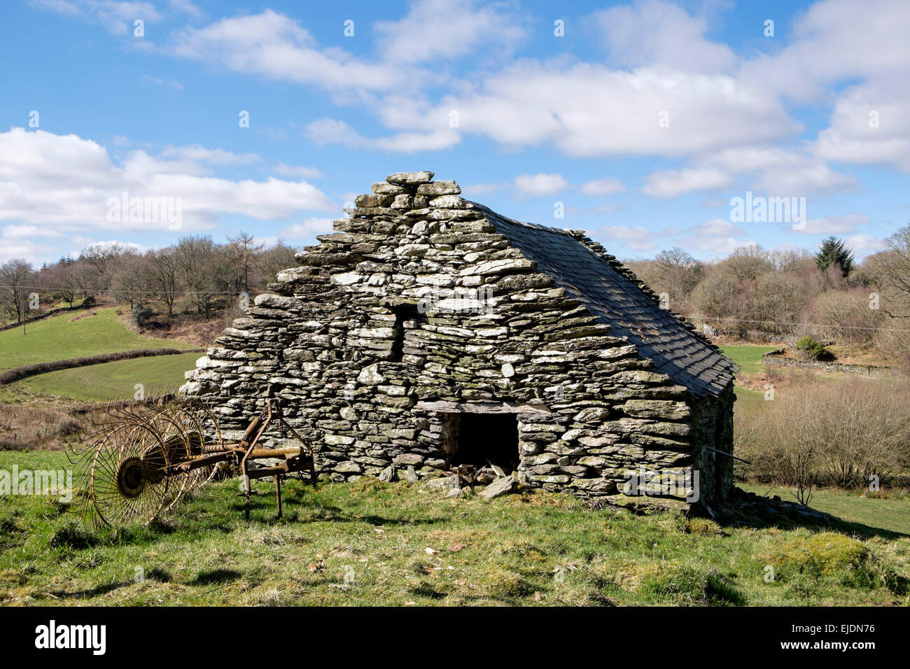 L'outillage agricole traditionnel vieux râteau à foin à l'extérieur une grange en pierre en campagne dans le Nord du Pays de Galles, Snowdonia, UK, Grande-Bretagne Banque D'Images