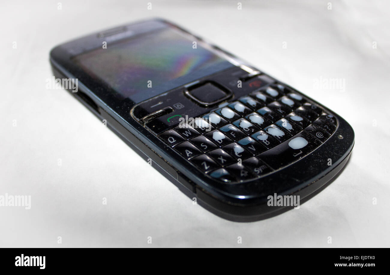 Vieux poussiéreux conseil qwerty téléphone mobile avec des boutons usé et des pièces manquantes. Banque D'Images