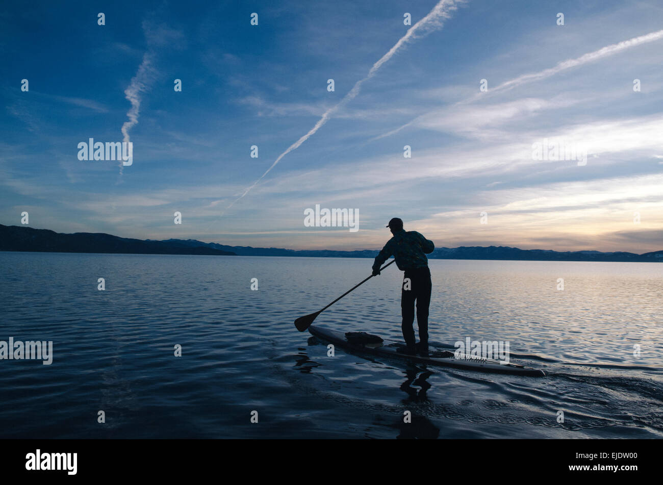 Un jeune homme stand-up paddleboards sur une froide et claire journée d'hiver de Lake Tahoe, Nevada. Banque D'Images