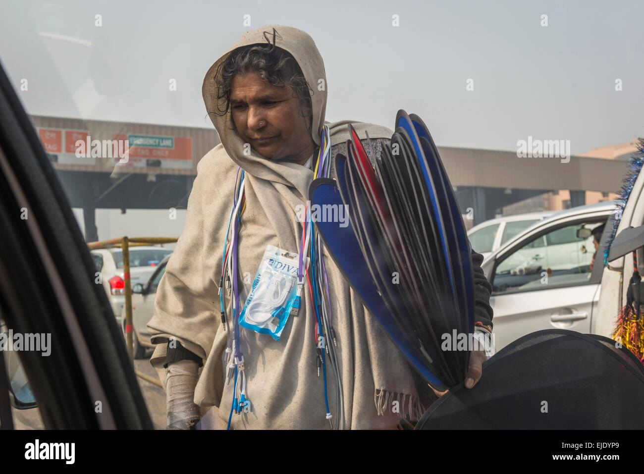 Femme vendant chargeurs de téléphones et d'écrans solaires à un péage routier sur une autoroute indienne Banque D'Images
