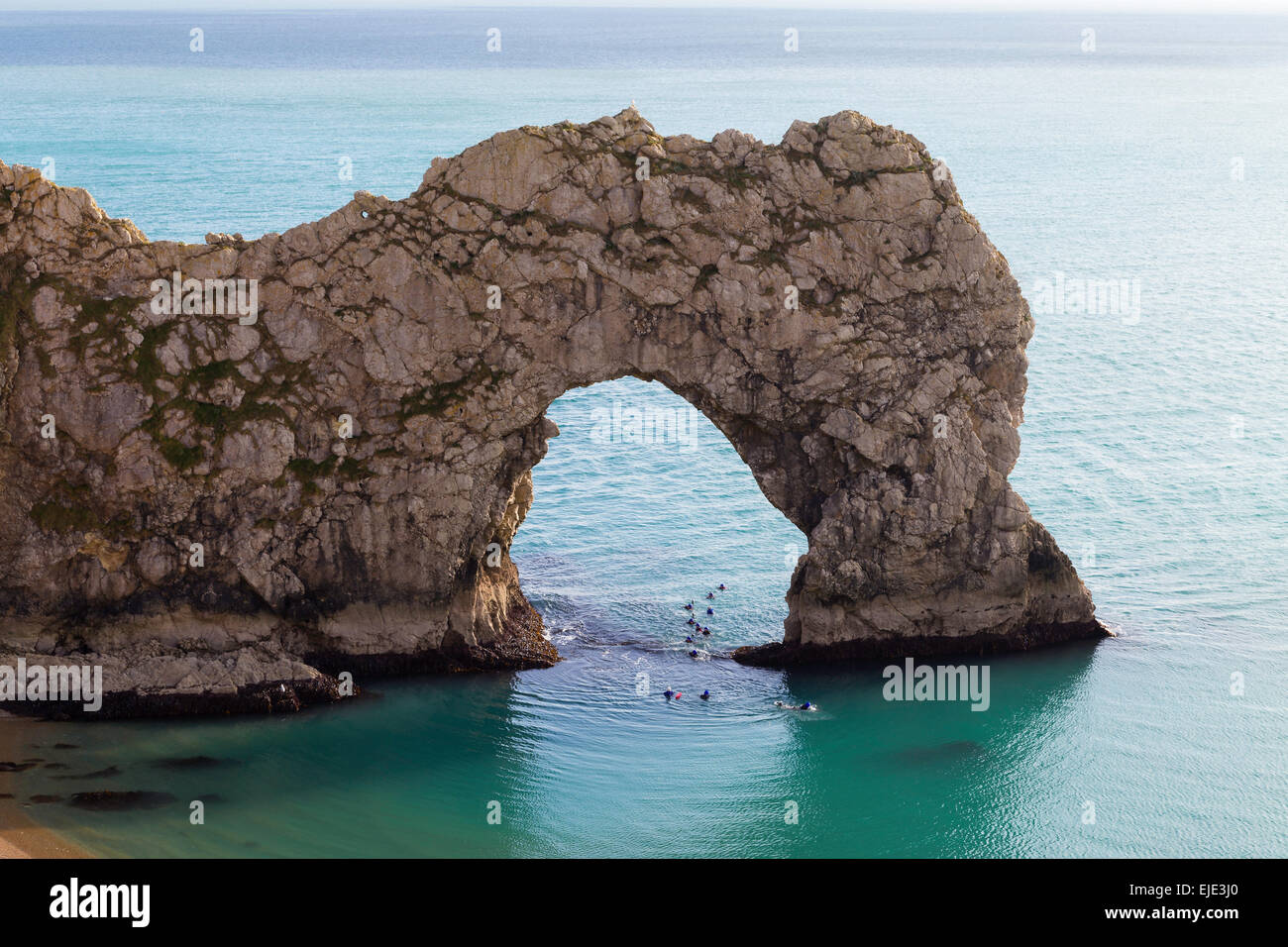 Le passage de la mer à Durdle Door sur la côte jurassique du Dorset sur une journée ensoleillée, calme. Les nageurs nagent dans l'arche. Banque D'Images