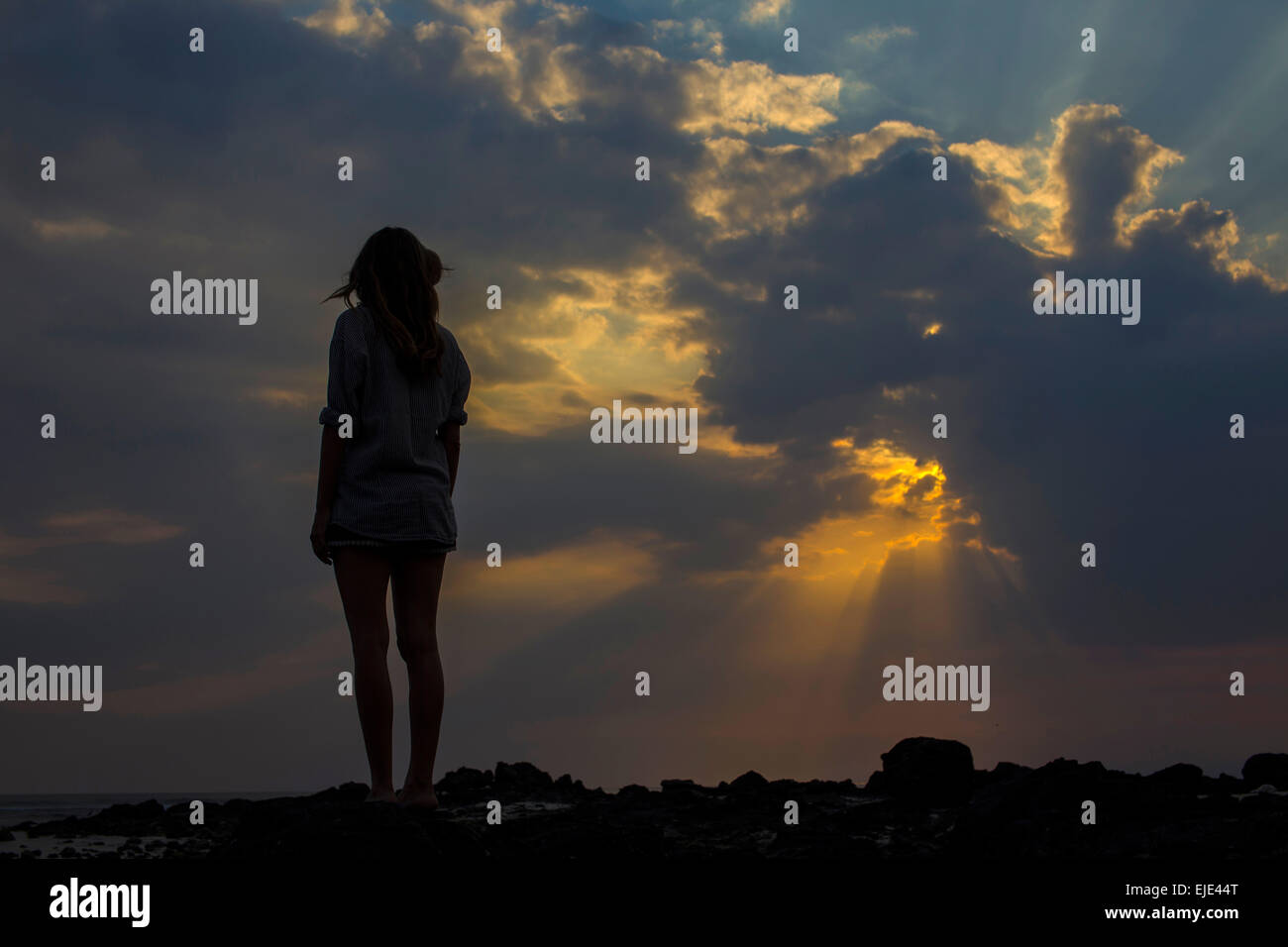Femme regarde le coucher du soleil dans l'océan. Banque D'Images Femme regarde le coucher du soleil dans l'océan. Banque D'Images