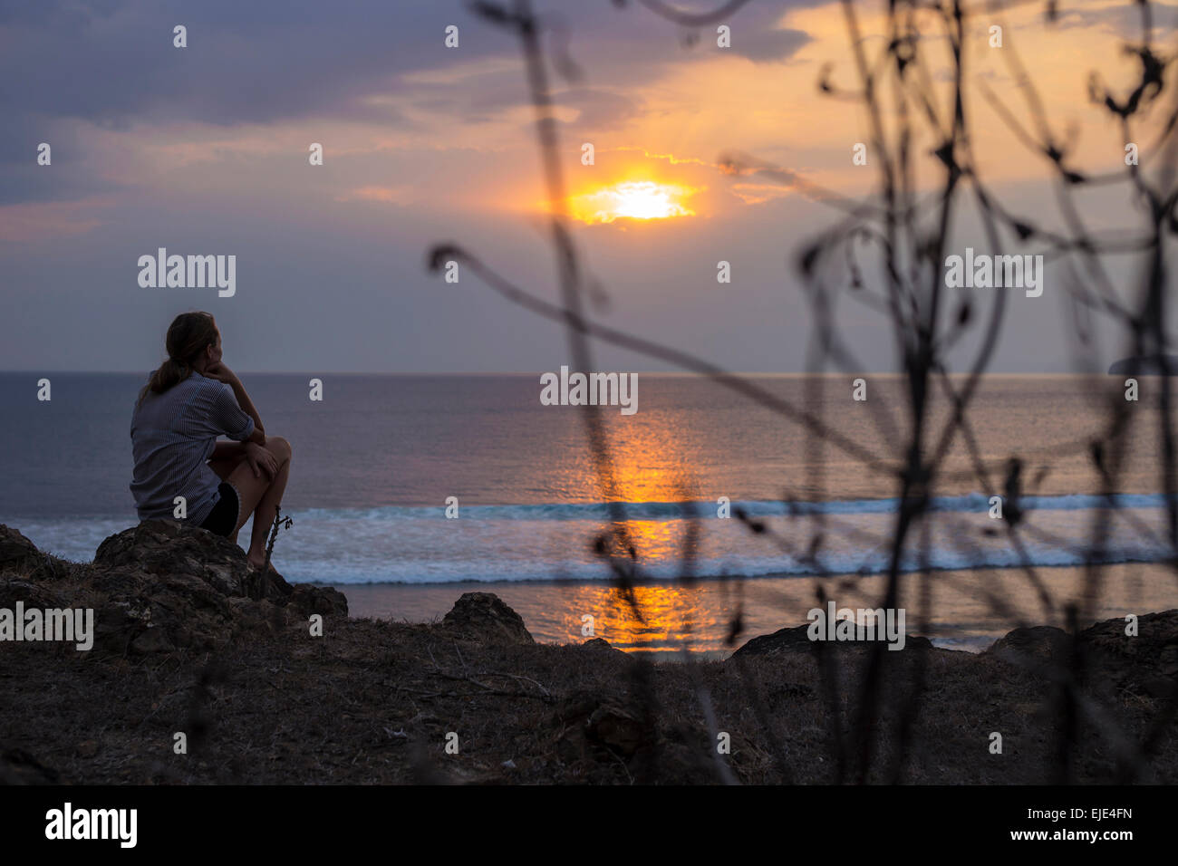Femme regarde le coucher du soleil dans l'océan. Banque D'Images Femme regarde le coucher du soleil dans l'océan. Banque D'Images