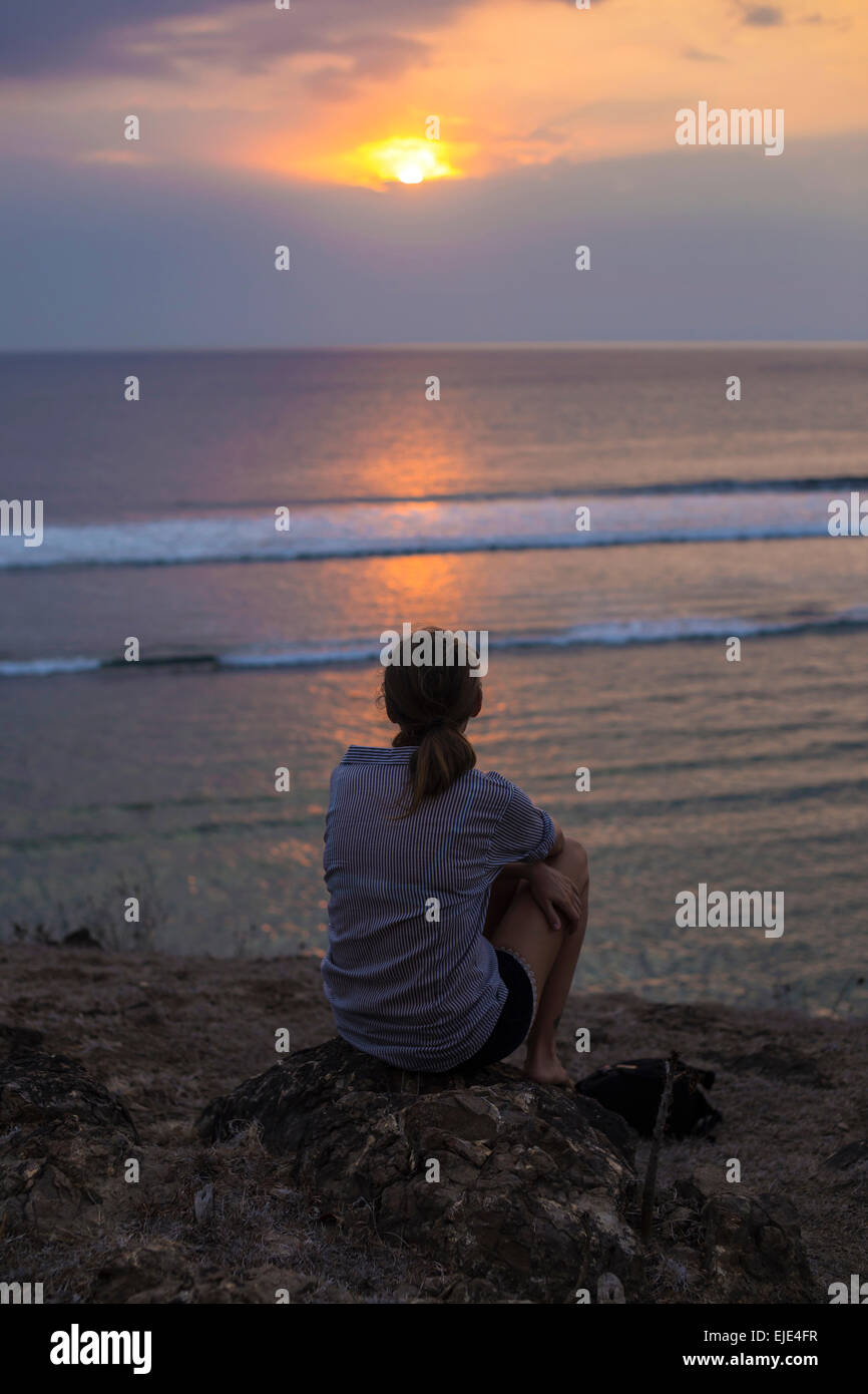 Femme regarde le coucher du soleil dans l'océan. Banque D'Images Femme regarde le coucher du soleil dans l'océan. Banque D'Images