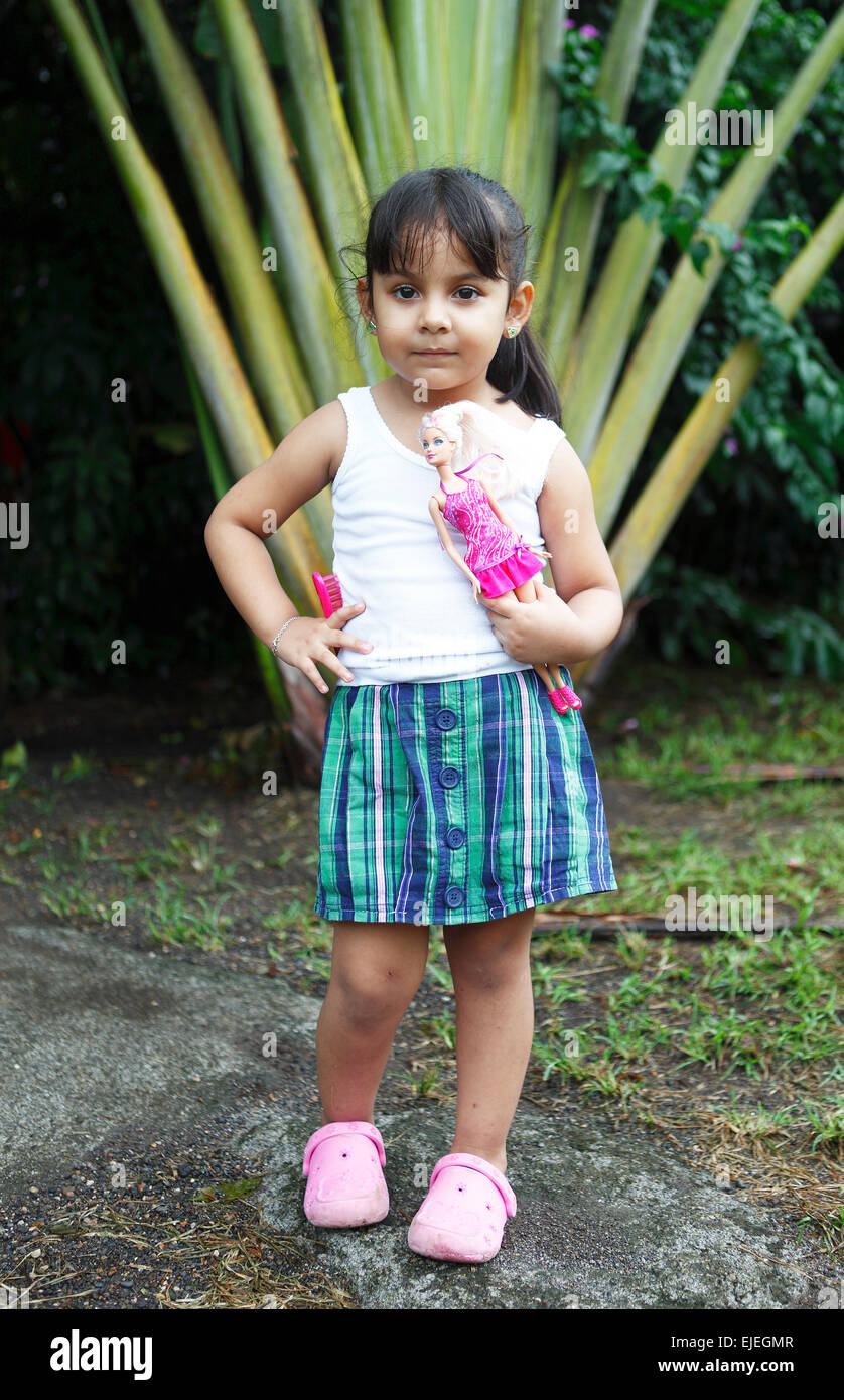 Fille, 4 ans, tenant une poupée Barbie, posant devant un palmier, San Juan de Nicaragua ou San Juan del Norte ou Greytown Banque D'Images