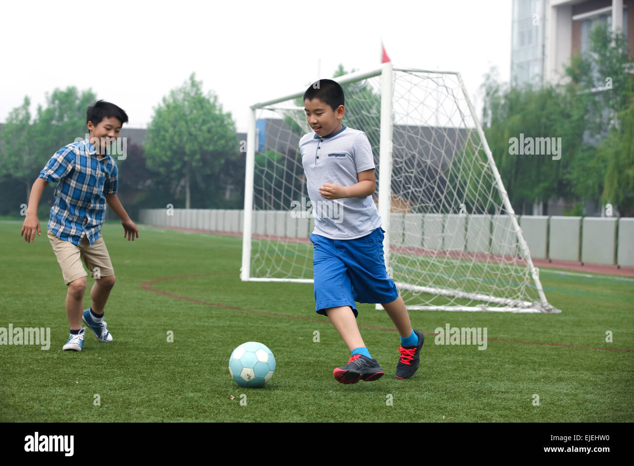 Deux garçons jouent au football sur le terrain de football Banque D'Images