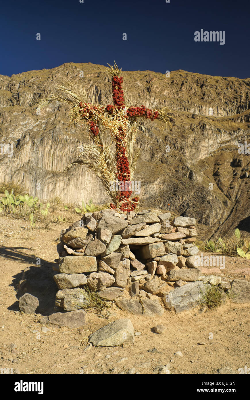 Croix chrétienne enroulé autour de fleurs sur le paysage aride du Pérou près de Canon del Colca Banque D'Images