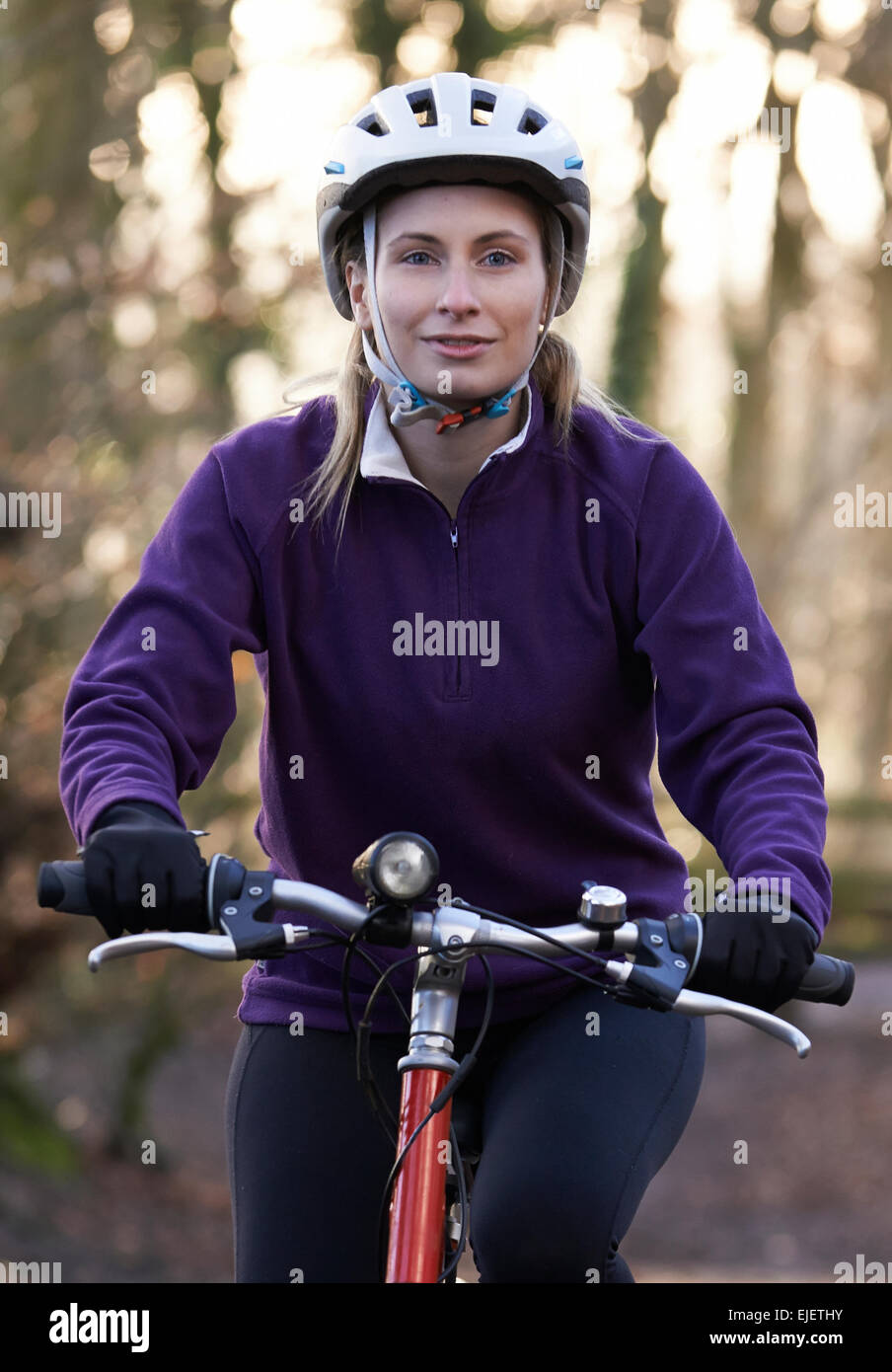 Woman Riding Mountain Bike à travers des bois Banque D'Images