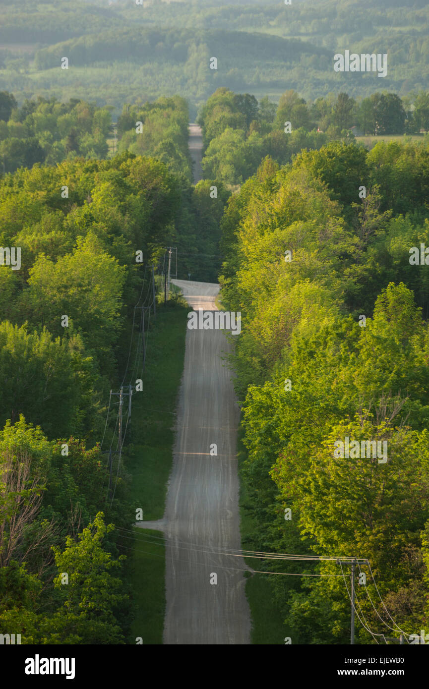 Une route de gravier en été conduit sur les collines boisées dans les régions rurales du sud de l'Ontario, Canada. Banque D'Images