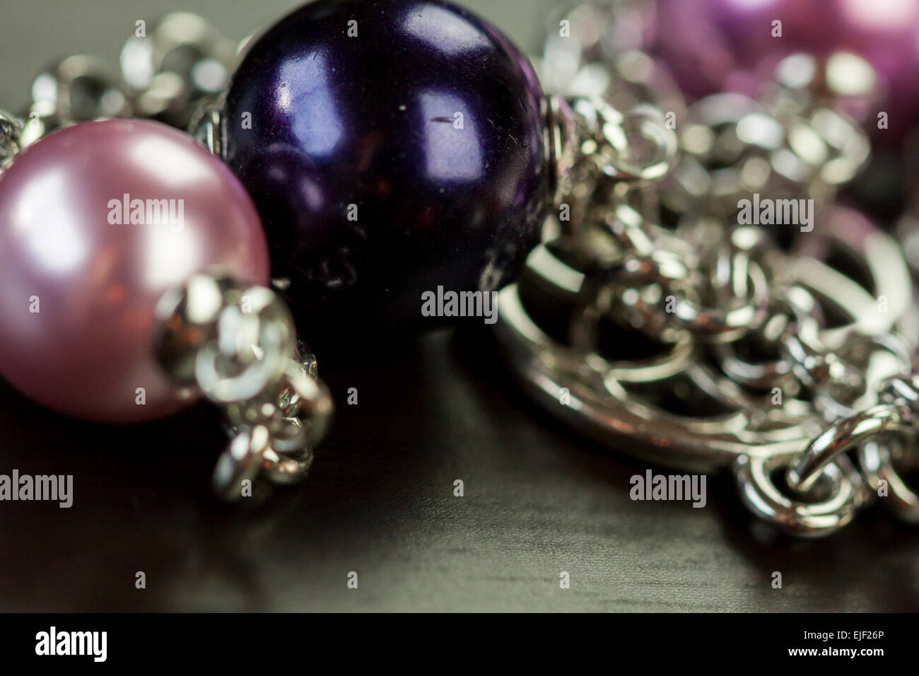 Close up de trois superbes perles violet brillant attaché par des chaînes d'argent sur un élément de bijoux dans un concept d'artisanat et de la mode Banque D'Images