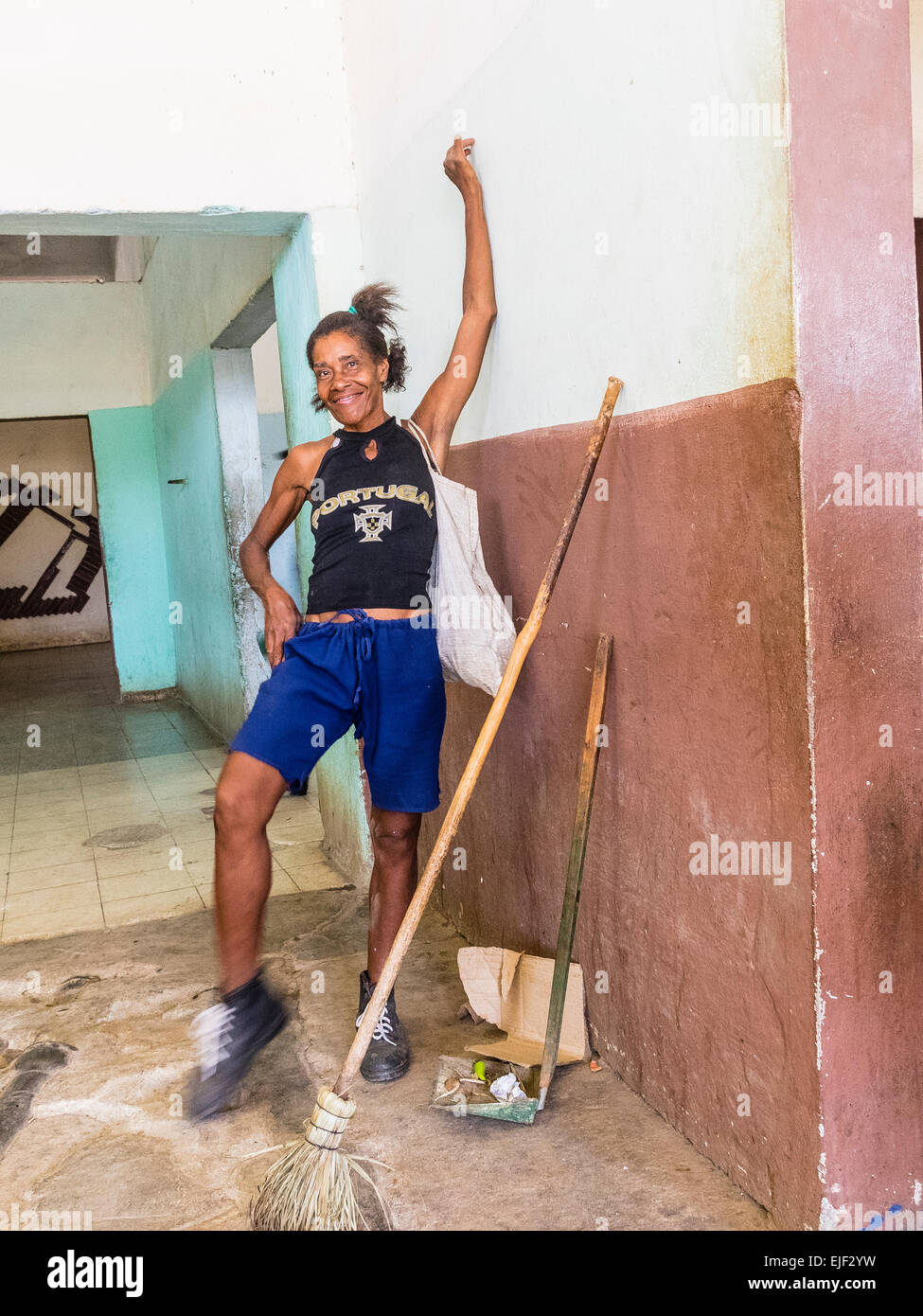 Une femme afro-cubaine femme de ménage pose et sourit alors qu'elle prend une pause de son travail de nettoyage sur le marché public. Banque D'Images
