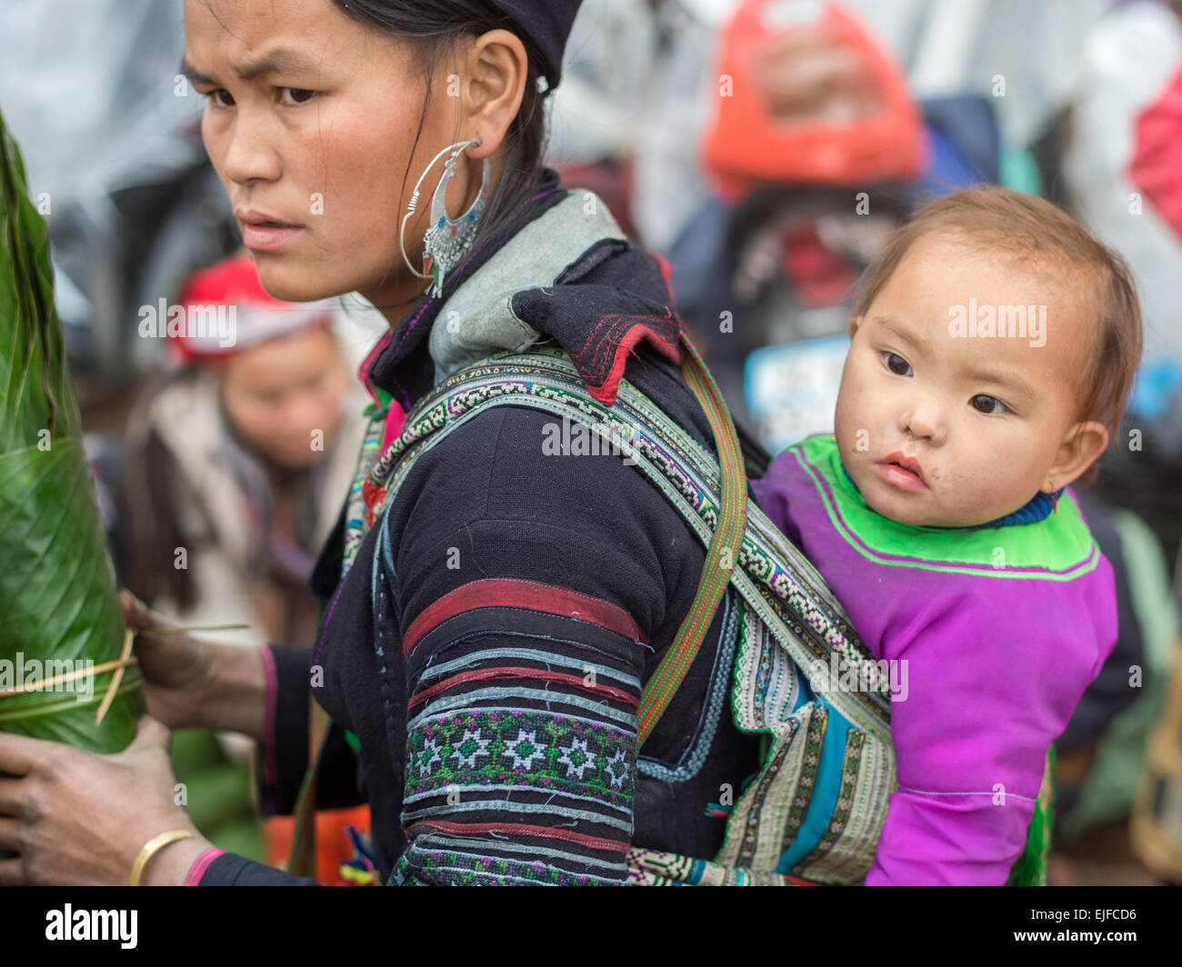 Jeune femme Hmong avec un enfant dans un marché de Sapa, Vietnam Banque D'Images