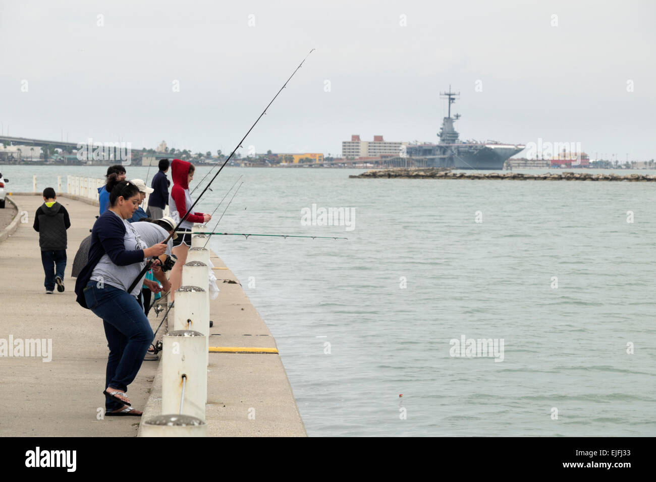 Hispanic Family la pêche dans la baie de Corpus Christi avec le U.S.S. Lexington en arrière-plan. Banque D'Images