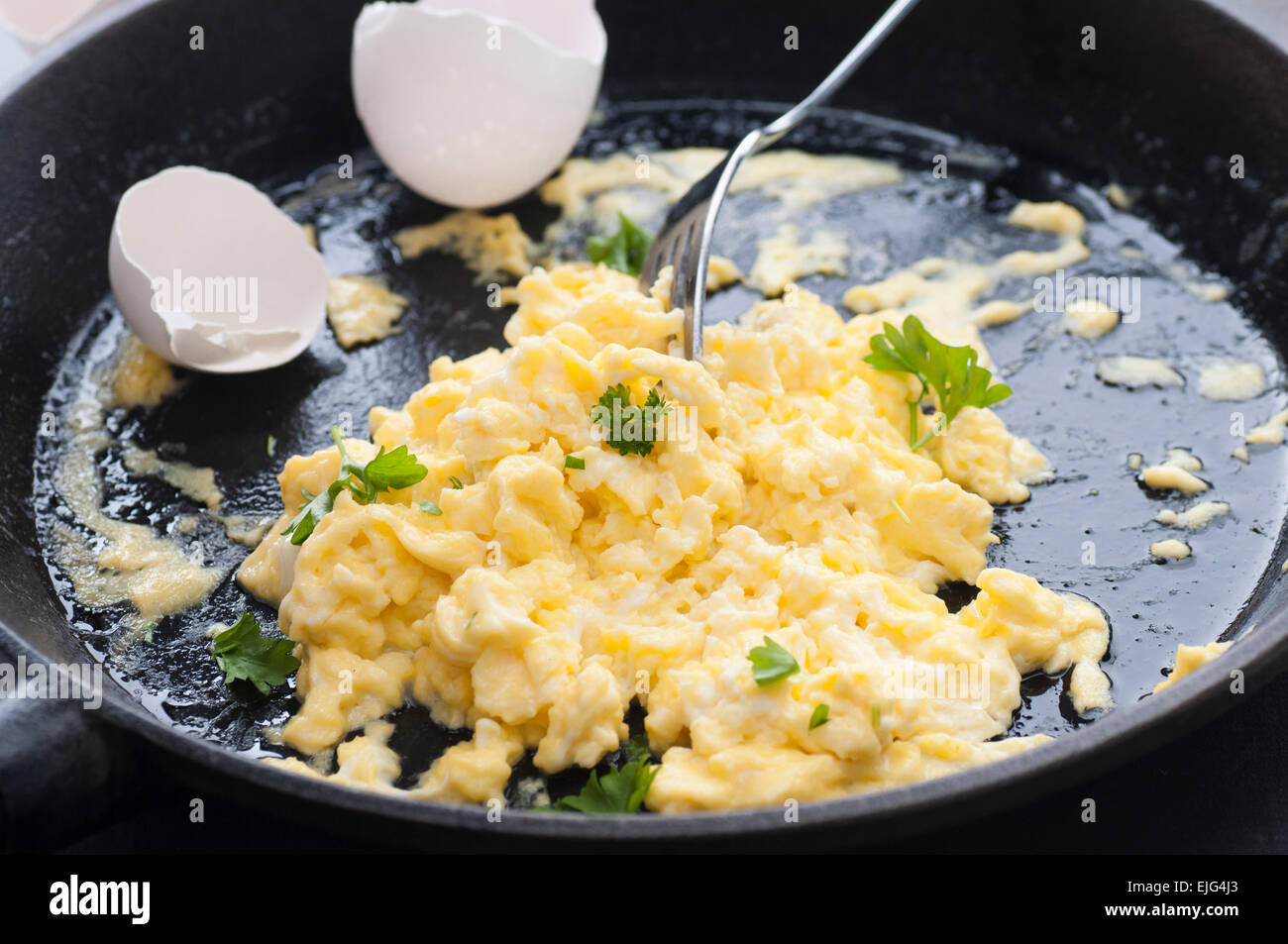 Brouillés les œufs avec la crème double, poêlés au beurre. Toutes les matières organiques. Le persil sur le dessus. Banque D'Images