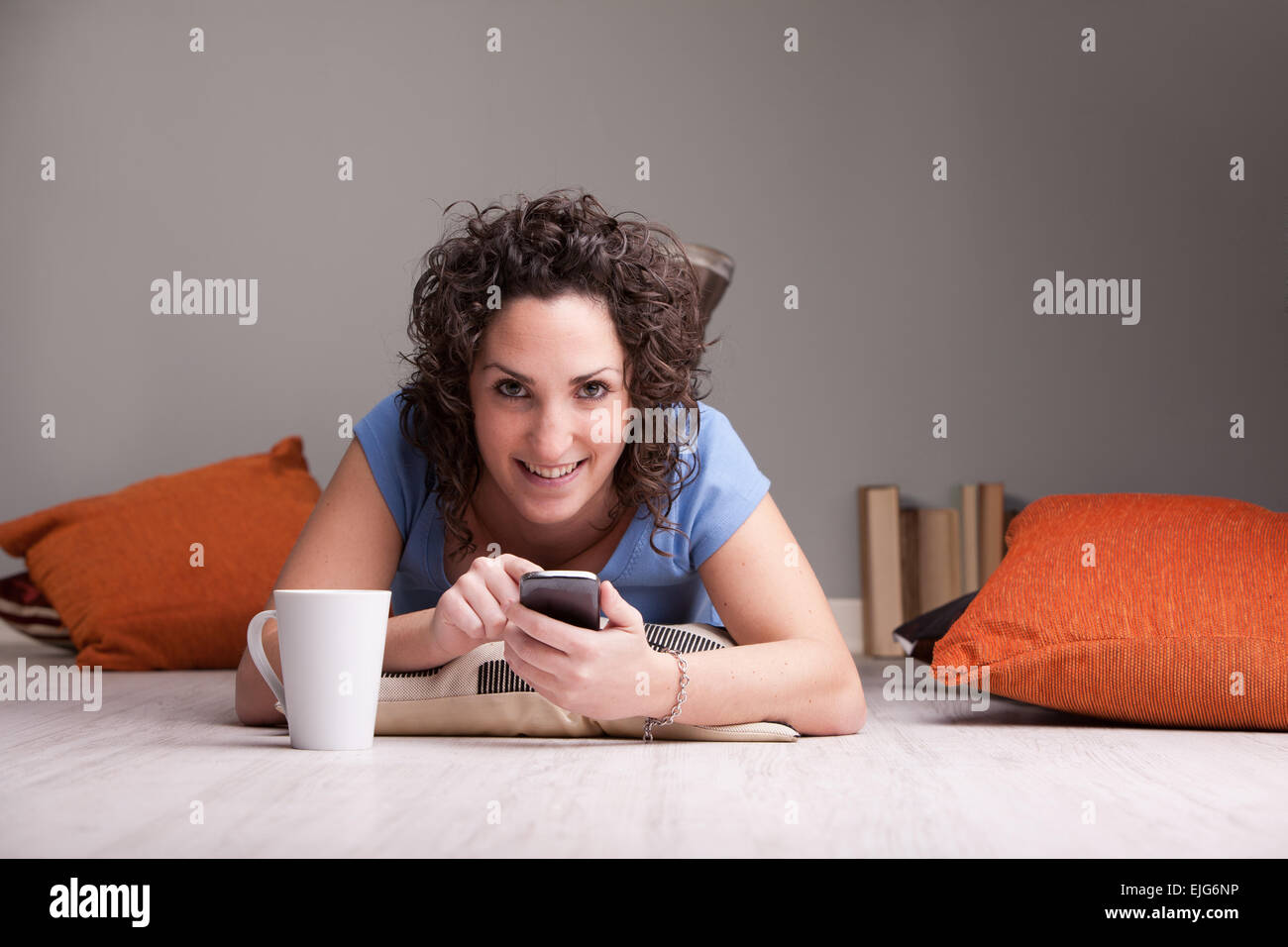 Girl enjoying son téléphone portable tout en buvant dans une tasse blanche Banque D'Images