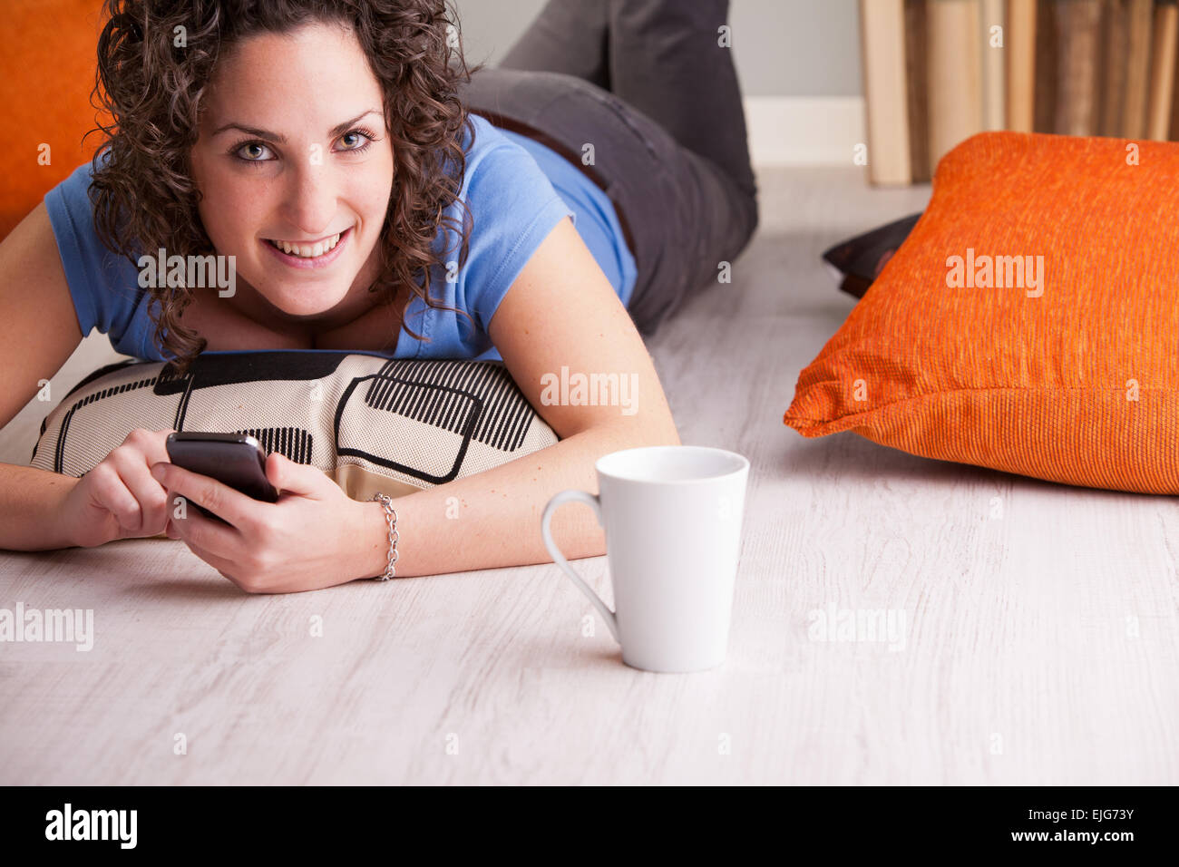 Girl enjoying son téléphone portable tout en buvant dans une tasse blanche Banque D'Images