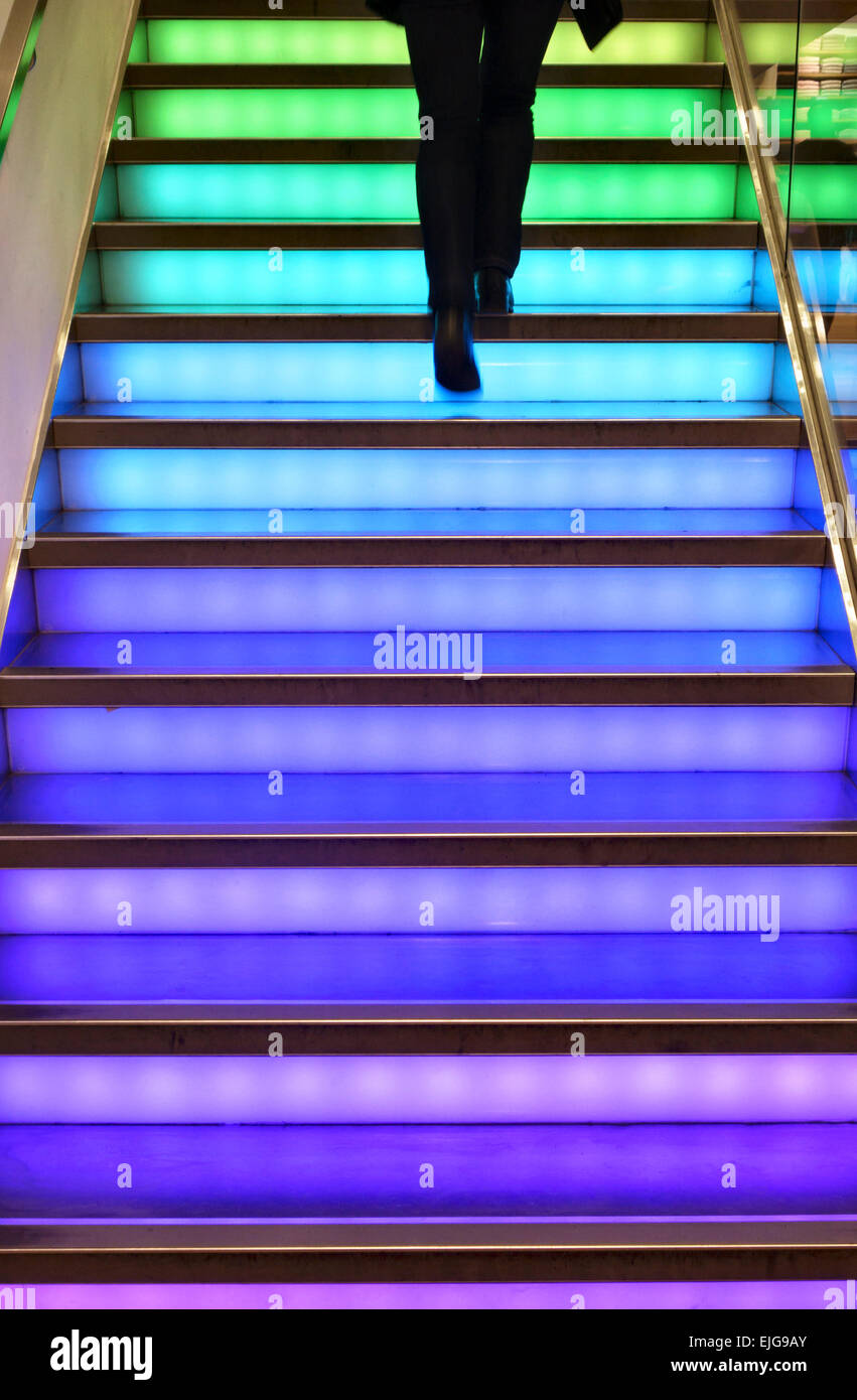 Un homme à monter un escalier lumineux colorés au fashion store Uniqlo, Regent Street dans le West End de Londres Banque D'Images