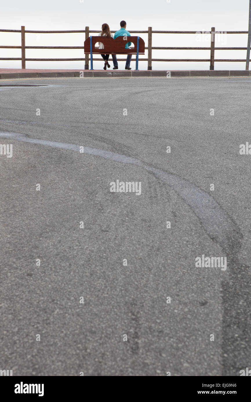 Silhouette d'un jeune couple hétérosexuel sur un jour nuageux calme et paisible, relaxant en face de l'ocean view Banque D'Images