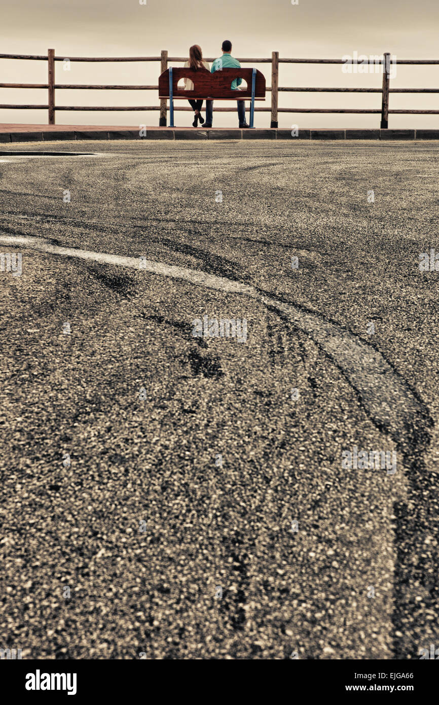 Silhouette d'un jeune couple hétérosexuel sur un jour nuageux calme et paisible, relaxant en face de l'ocean view Banque D'Images