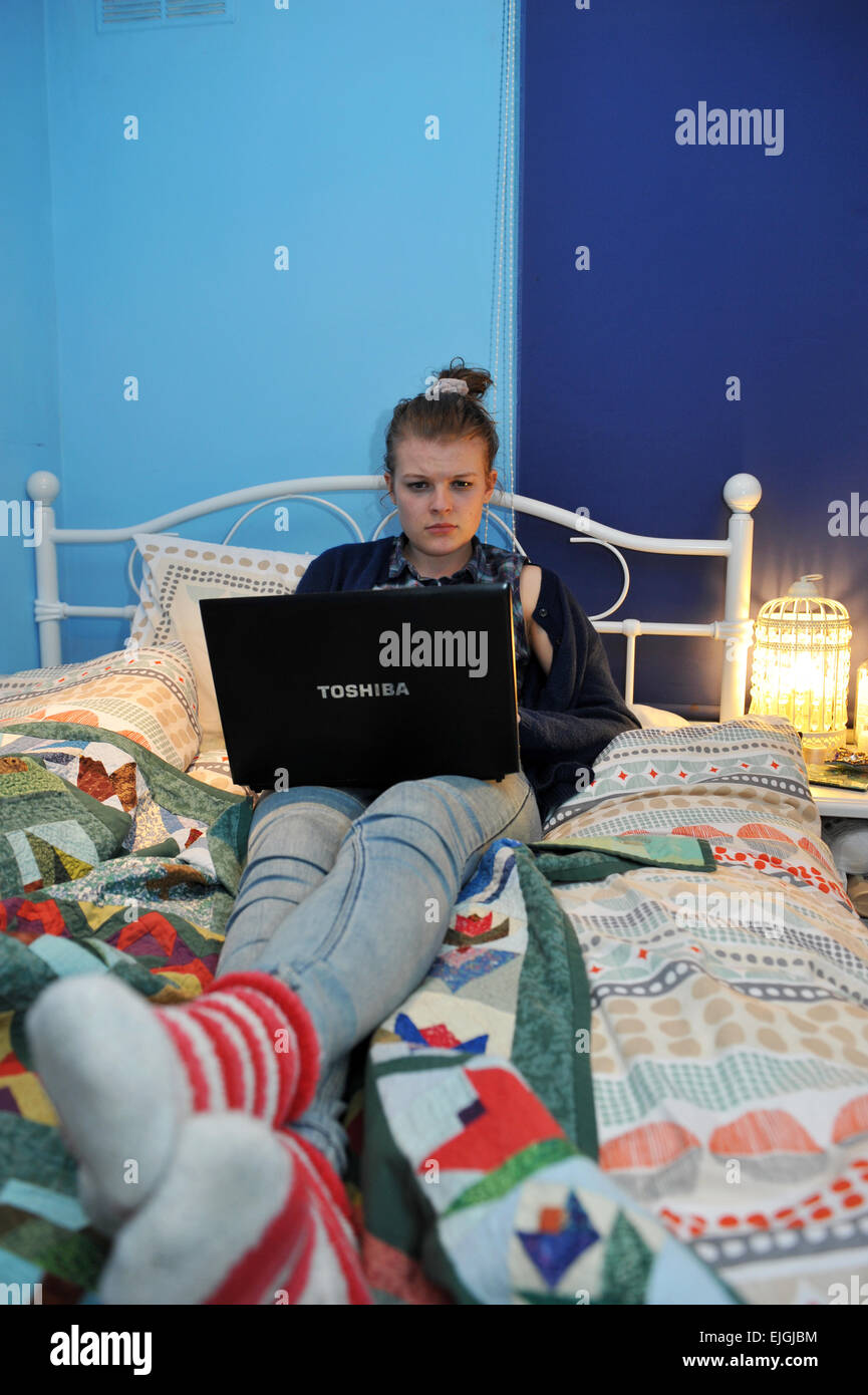 Adolescente surfe sur internet à partir de sa chambre. Banque D'Images