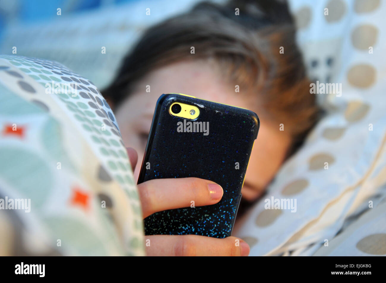 Teenage girl utilise son téléphone portable la nuit au lit. Banque D'Images
