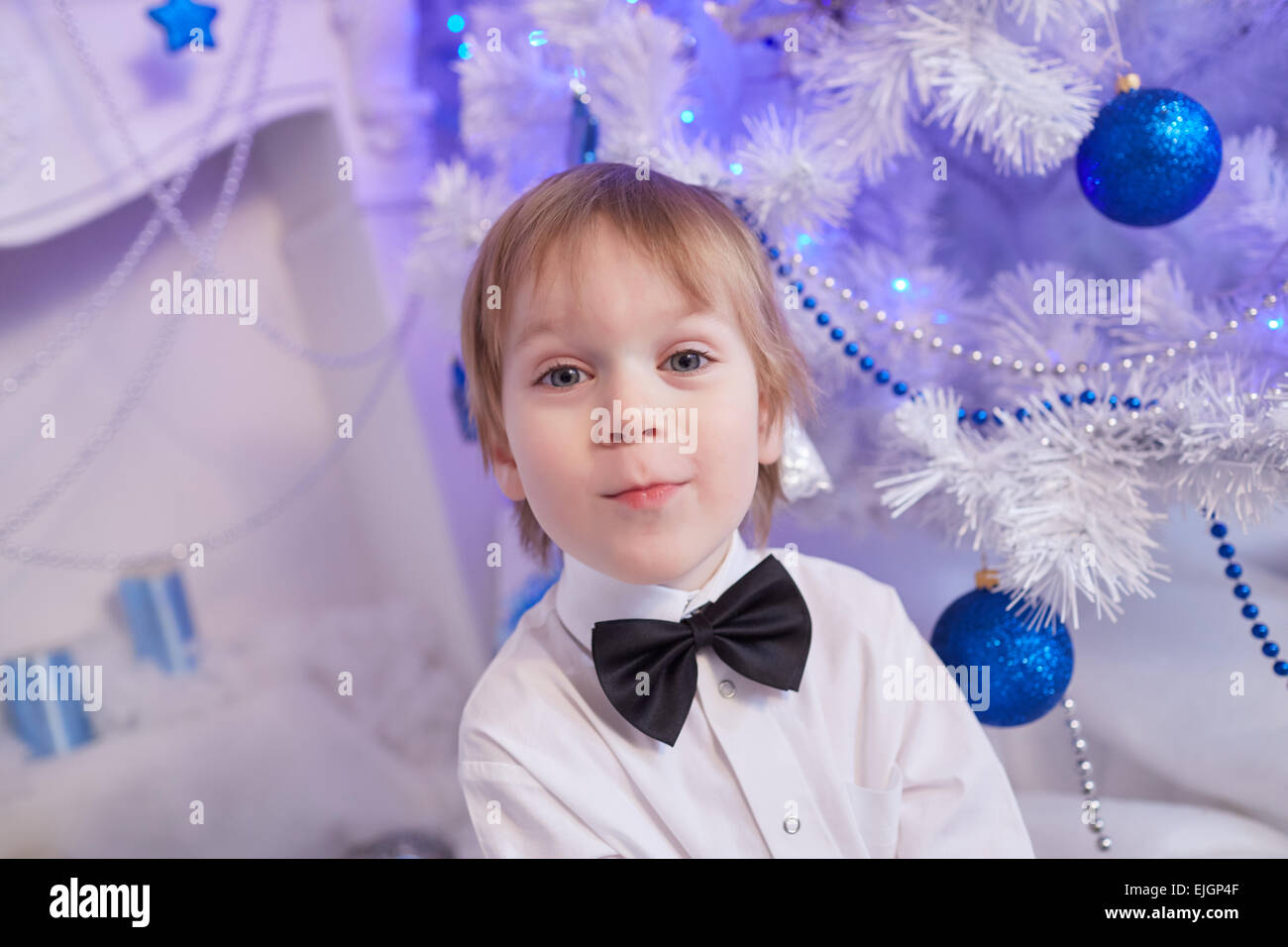 Garçon de cinq ans en prévision d'un don, assis près de l'arbre de Noël Banque D'Images