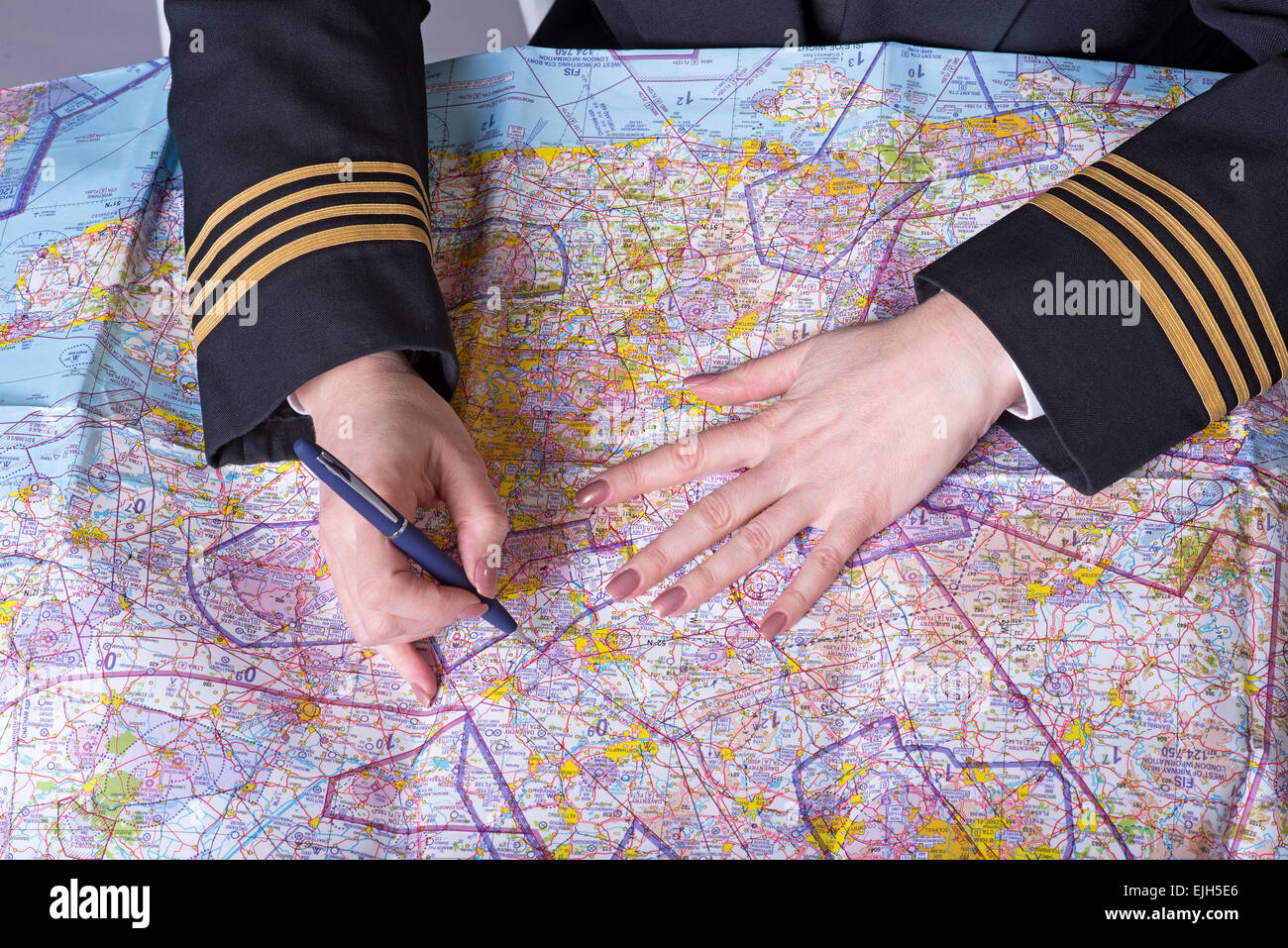 Agent de la compagnie aérienne portant quatre anneaux de tresse d'or sur le manchon de la planification d'un itinéraire Banque D'Images