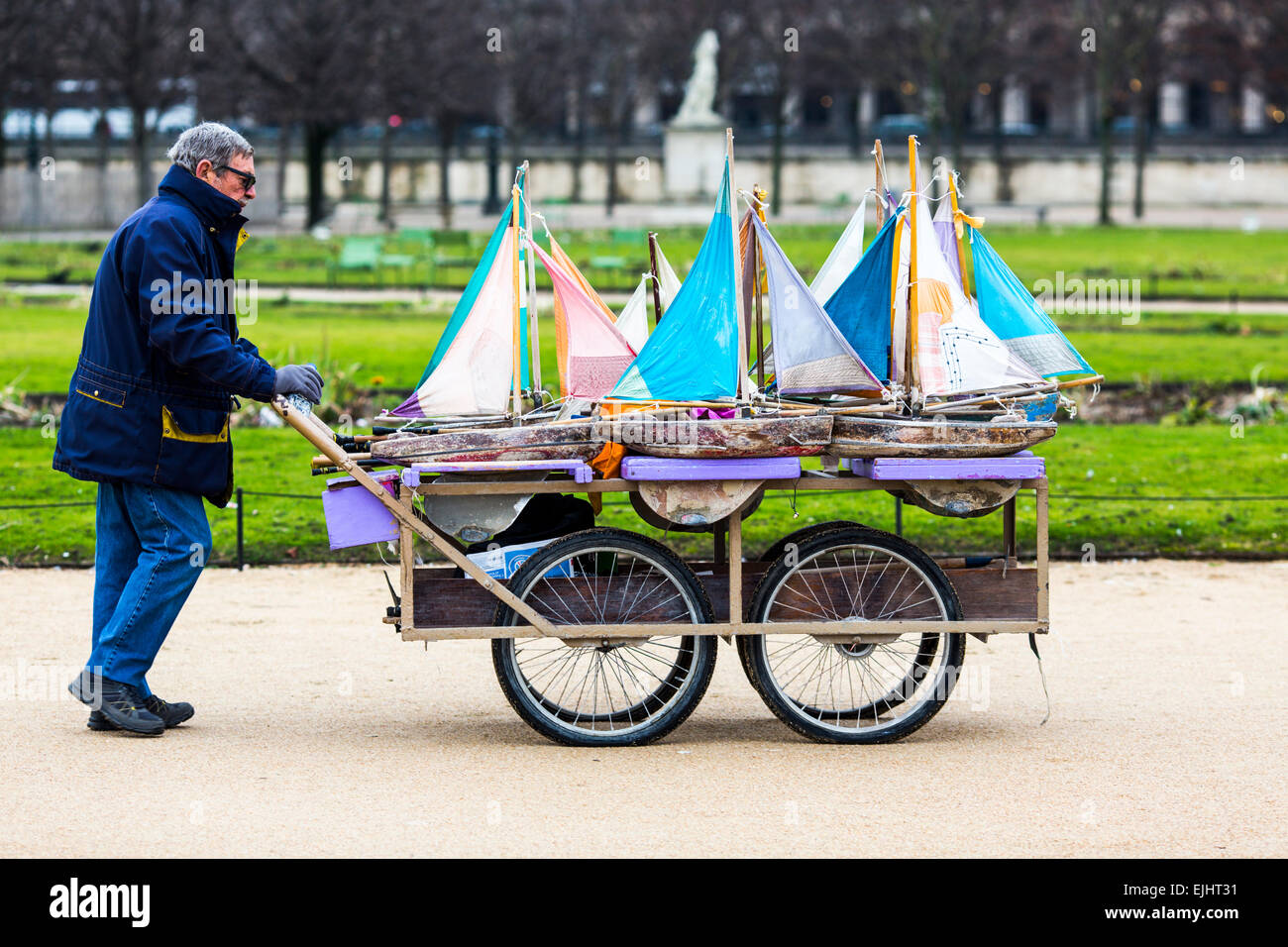 Homme avec panier jouet transportant des voiliers dans le jardin des Tuileries, Paris, France Banque D'Images