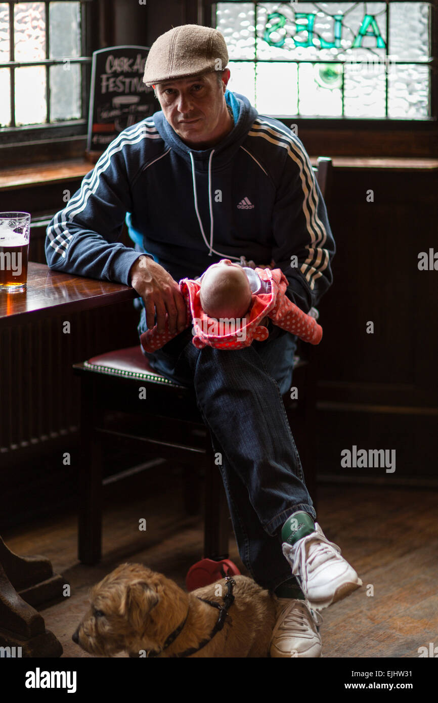 Homme de pub holding baby, chien à pieds, Londres, Angleterre Banque D'Images