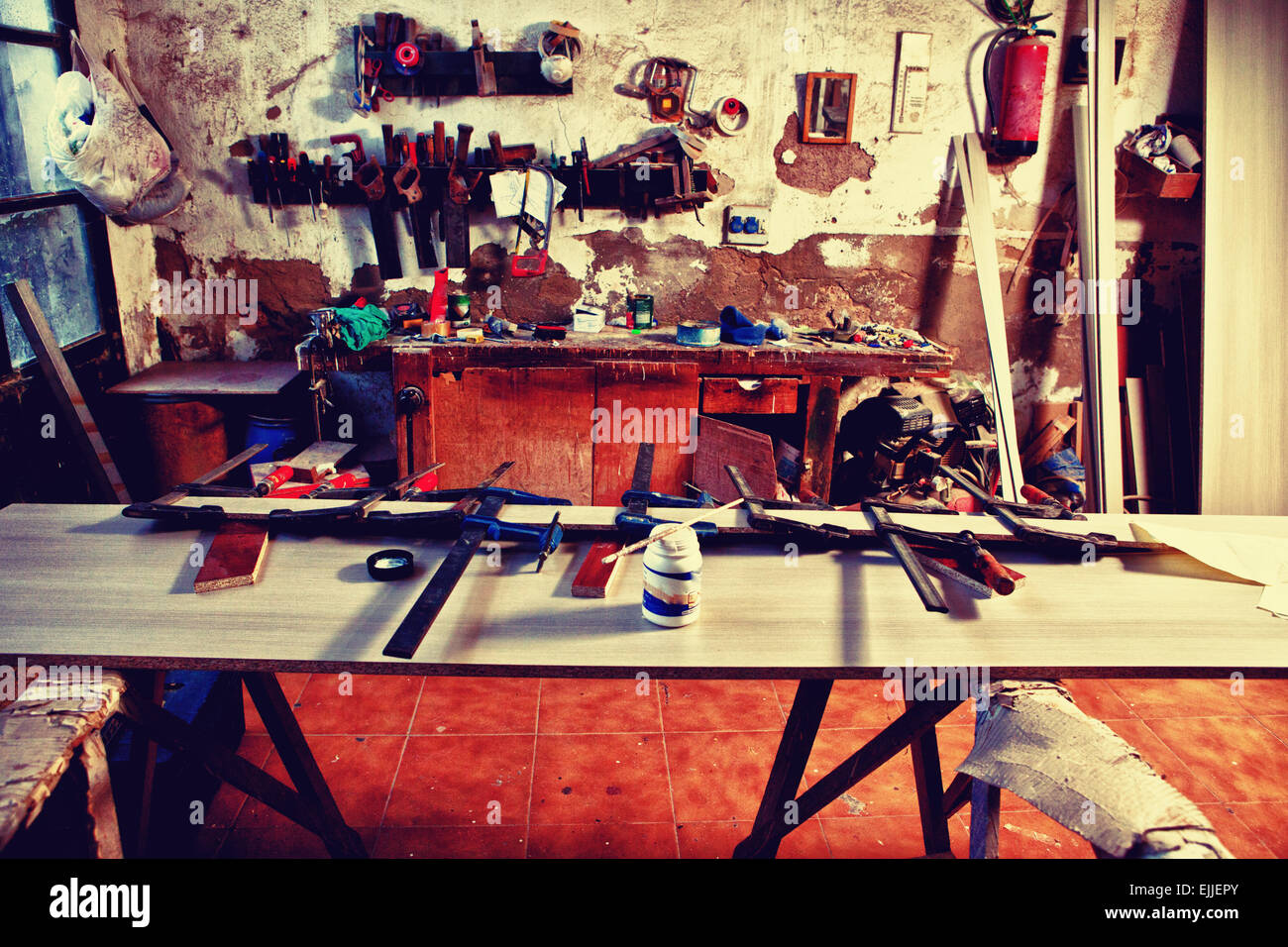 Ancien atelier de charpentier poussiéreux avec une table pleine de colliers Banque D'Images