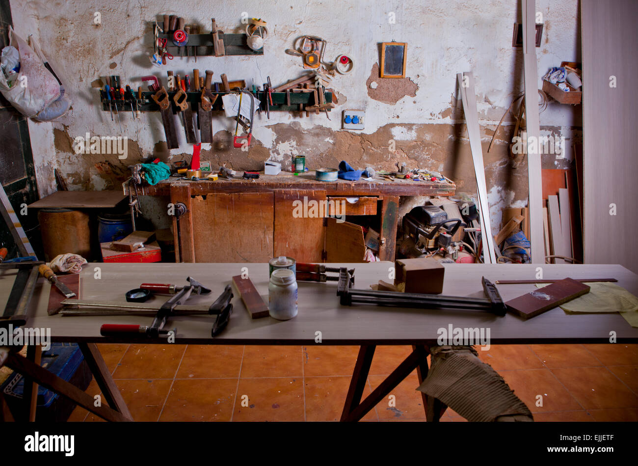 Ancien atelier de charpentier poussiéreux avec une table pleine de colliers Banque D'Images
