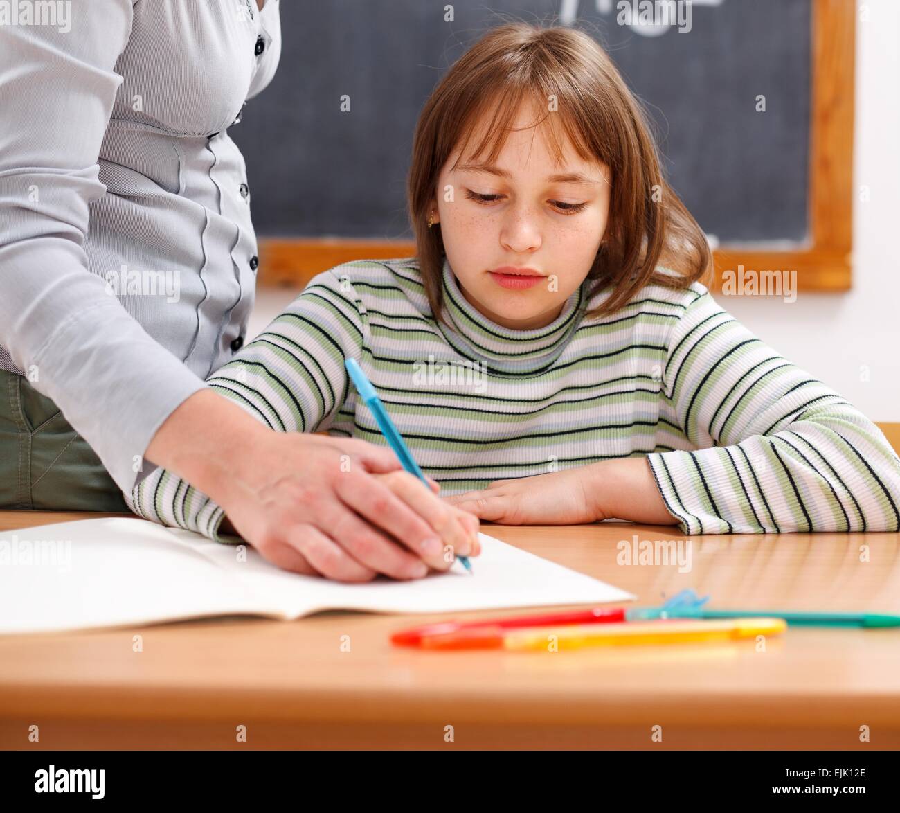 Montrant l'enseignant écrit par holding hand d'école primaire Banque D'Images