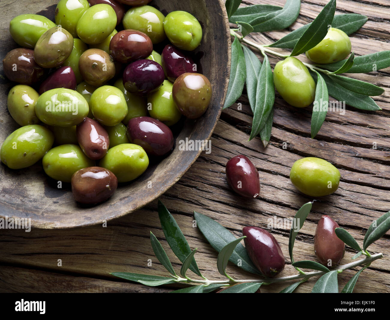 Bol en bois plein d'olives et les brindilles. Banque D'Images