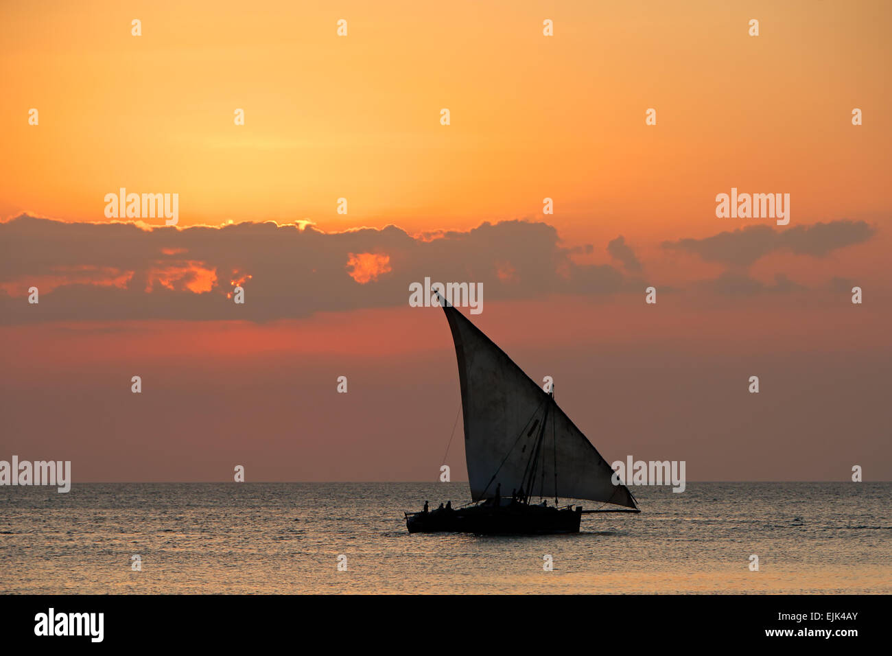 Voilier (dhow) sur l'eau au coucher du soleil avec les nuages, l'île de Zanzibar Banque D'Images