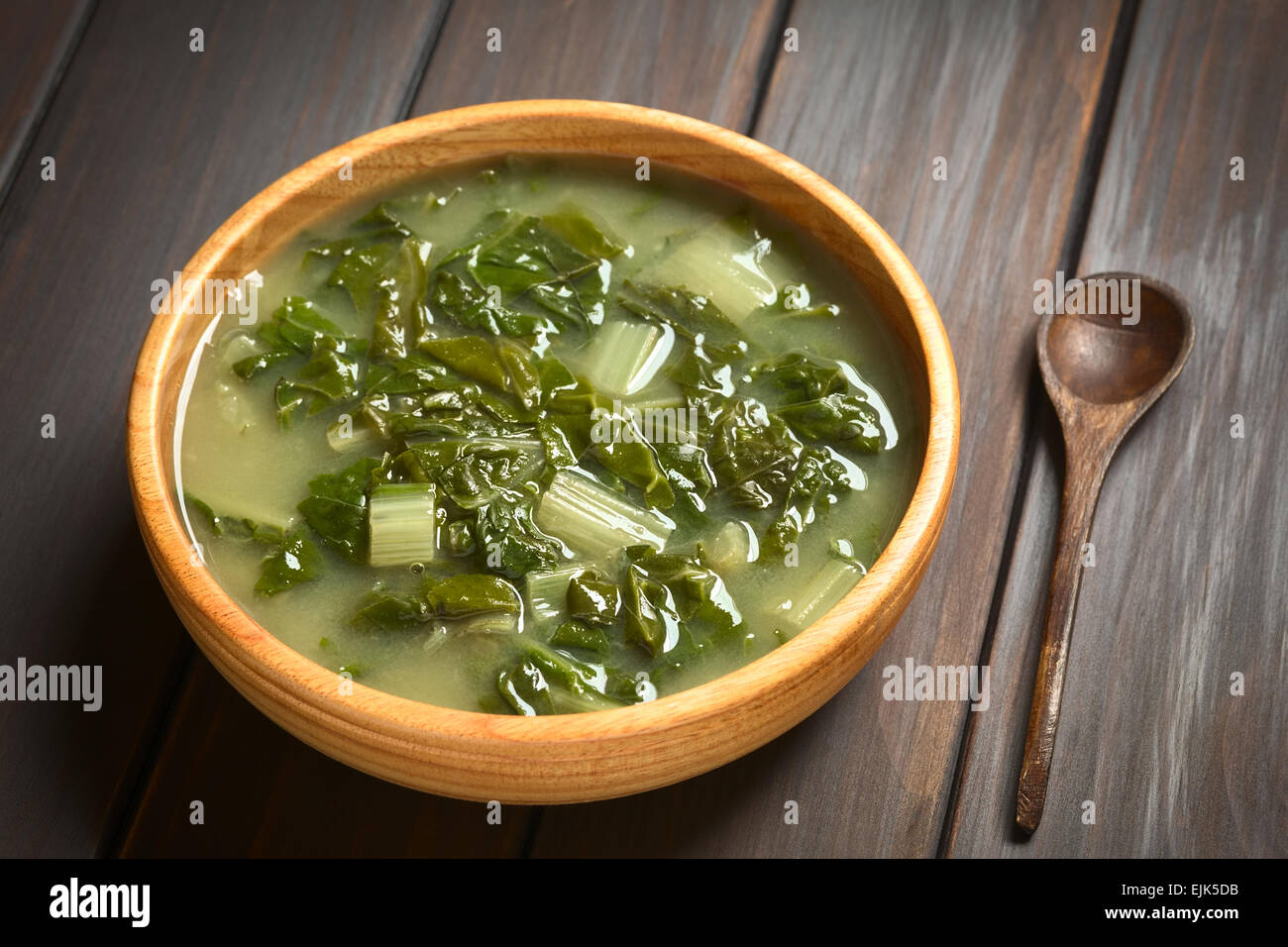 Soupe de blettes dans bol en bois avec une petite cuillère en bois, photographié sur bois foncé avec lumière naturelle (Selective Focus) Banque D'Images