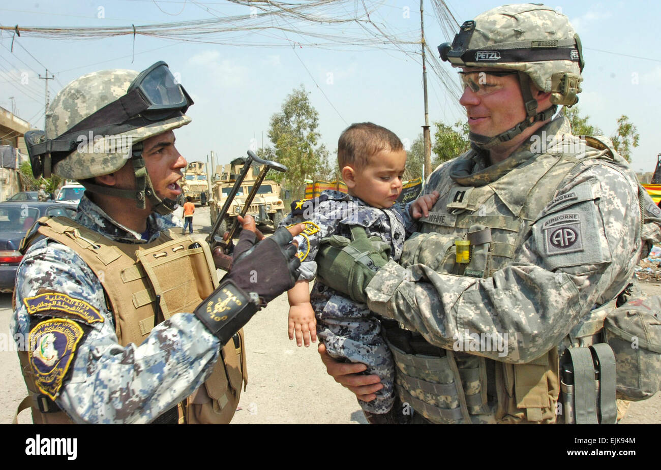 Le capitaine droit blanc d'argile, commandant de la Compagnie C, 2e Bataillon du 505th Parachute Infantry Regiment, 3e Brigade Combat Team, 82e Division aéroportée, Multi-National Division-Baghdad, parle à un agent de la Police nationale en tant qu'il porte un enfant iraquien portant un uniforme NP à la suite d'une distribution de fournitures scolaires 1 avril dans le district de Nissan 9 l'est de Bagdad. Blanc, et de parachutistes ont été invités par les responsables irakiens à participer à la Journée nationale de l'ensemble de l'Iraq. Orphelin Les responsables irakiens ont distribué des vêtements et des fournitures scolaires à plus de 60 enfants dans une école 9 Nissan. Banque D'Images