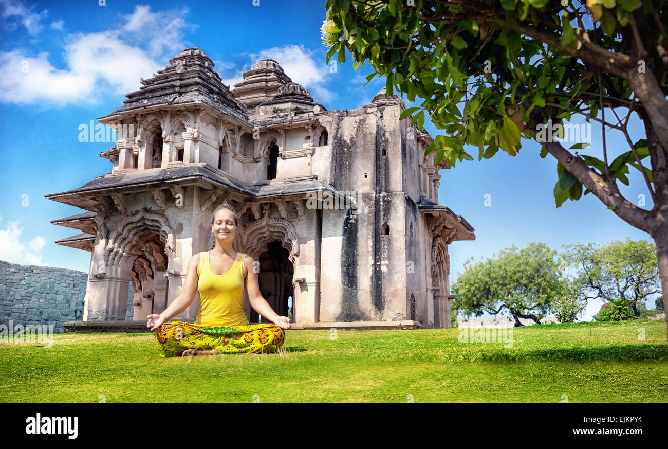 Woman doing yoga près de Lotus Mahal en centre royal au ciel bleu à Hampi, Karnataka, Inde Banque D'Images