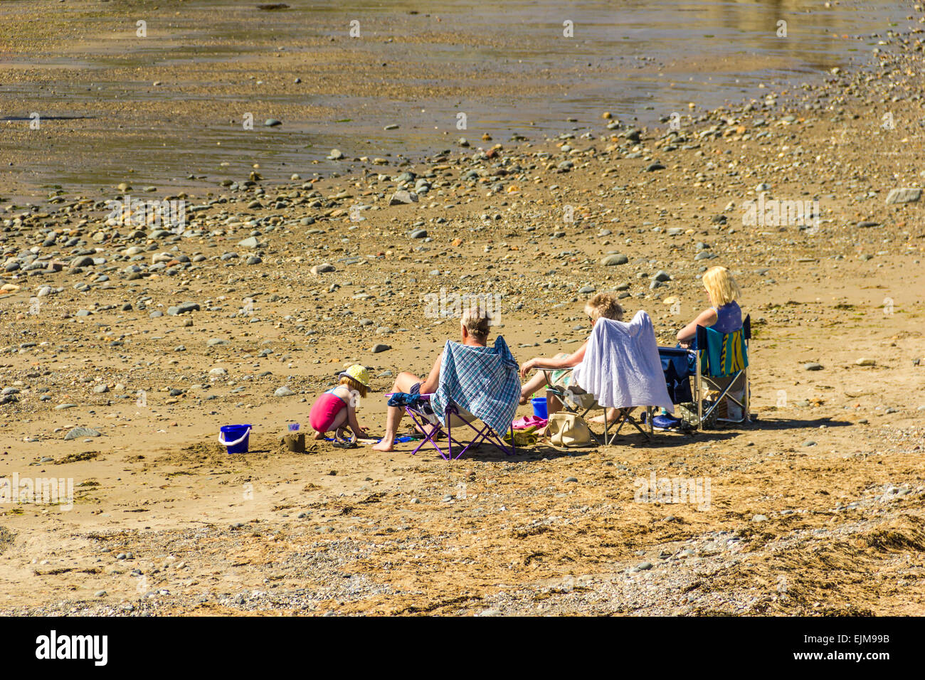Les gens en train de bronzer sur la plage de l'Est à Criccieth, Nord du Pays de Galles. Banque D'Images