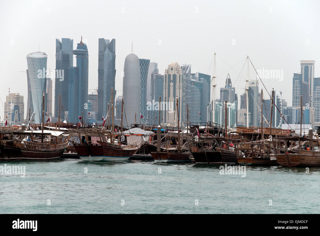 Une flotte de bateau dhow quai dans un port, à l'horizon de Doha, Qatar, en arrière-plan. Banque D'Images