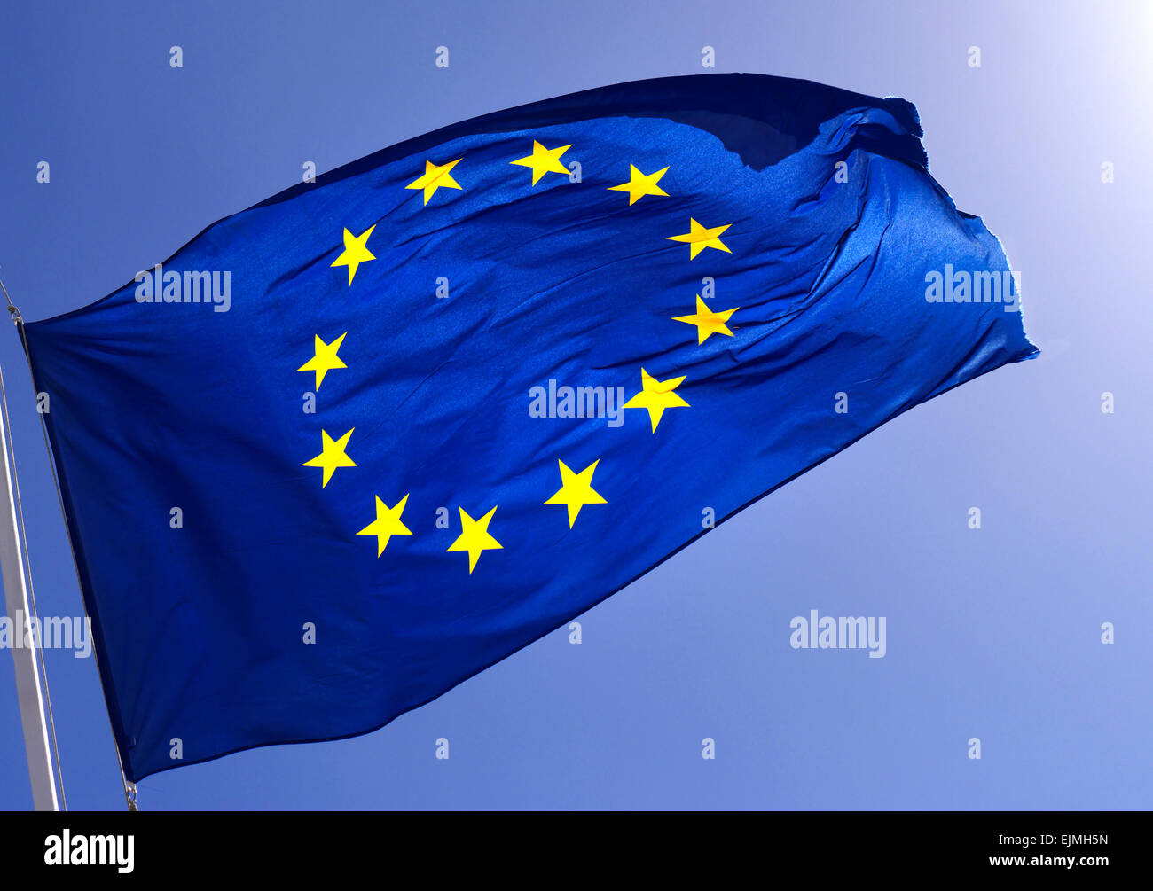 Drapeau de l'UE ciel bleu ensoleillé bold smart Communauté européenne l'Union flag flying voletant dans la brise geler une action contre un rétro-éclairé bleu ciel clair Banque D'Images