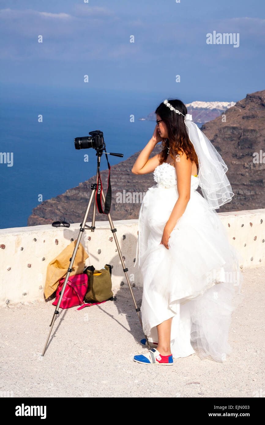 Jeune chinoise dans une robe de mariage en prenant des photographies, Firostefani, Santorin (Théra), Grèce. Banque D'Images