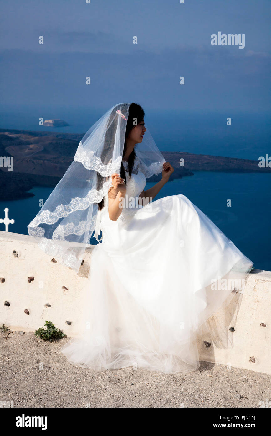 Jeune chinoise portant une robe de mariage traditionnelle et le voile qui pose pour photos avant-mariage, Firostefani, Santorin (Théra), Grèce. Banque D'Images